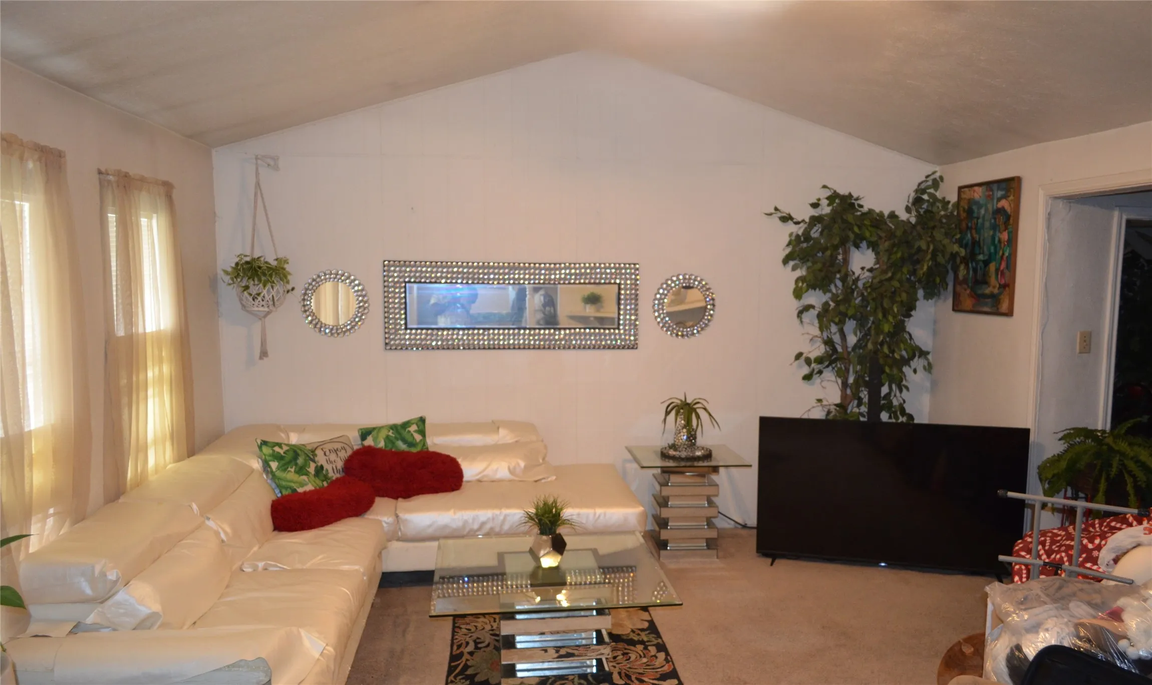 Vaulted ceiling living area featuring a large window, light-toned wall finishes, and carpet flooring