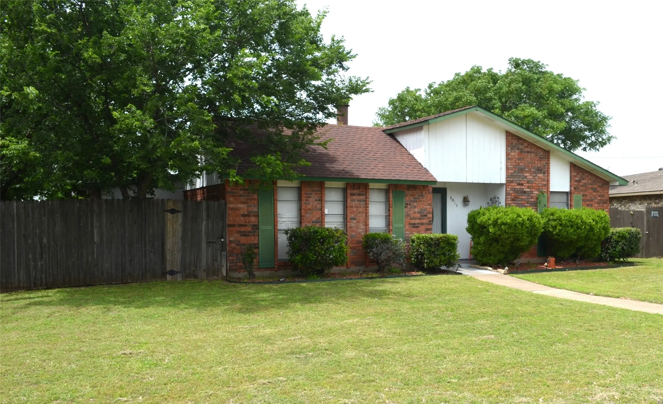 Brick exterior with white siding accents and a brown shingle roof