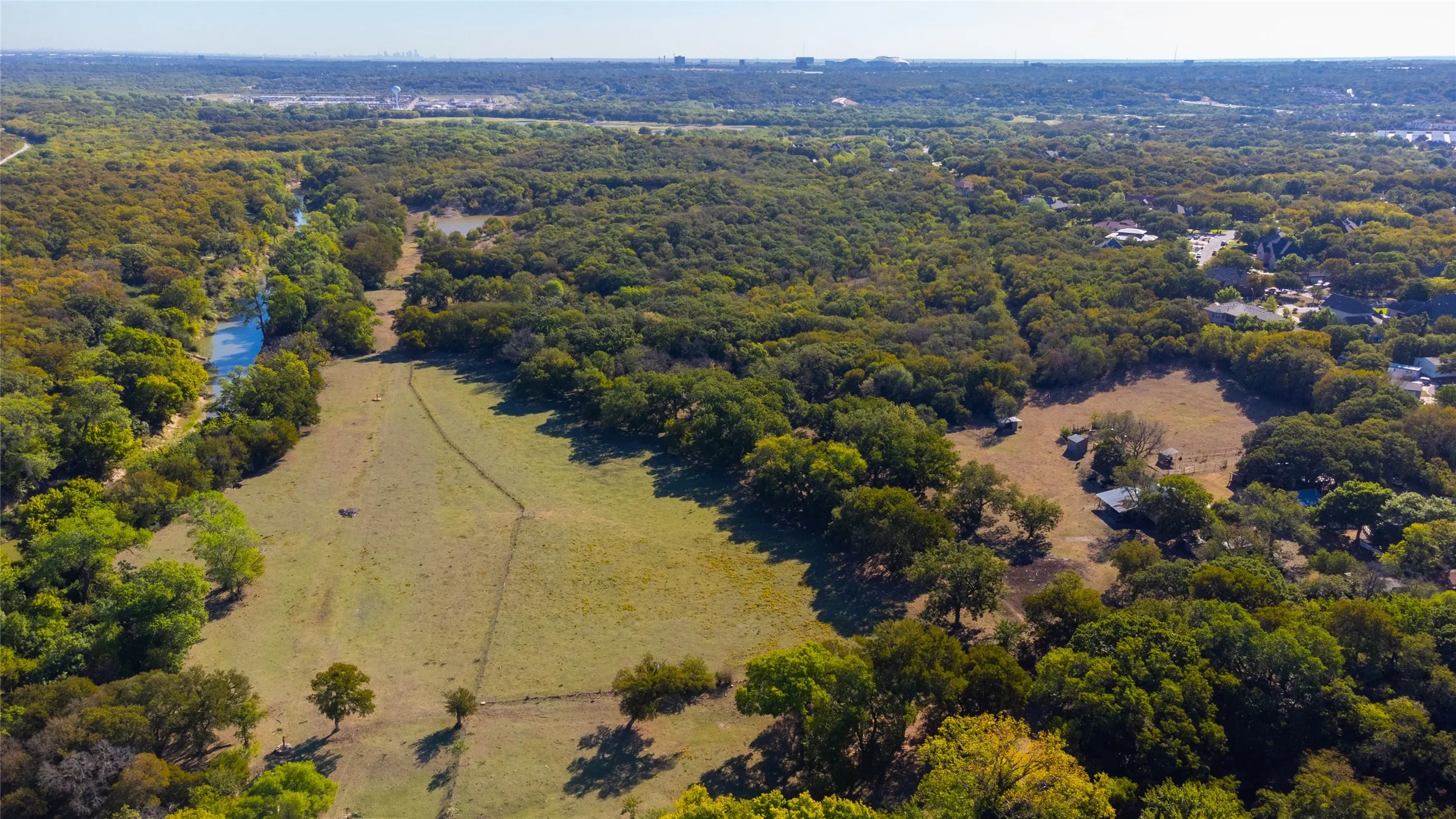 Expansive acreage featuring abundant mature trees, a natural watercourse, and established open fields