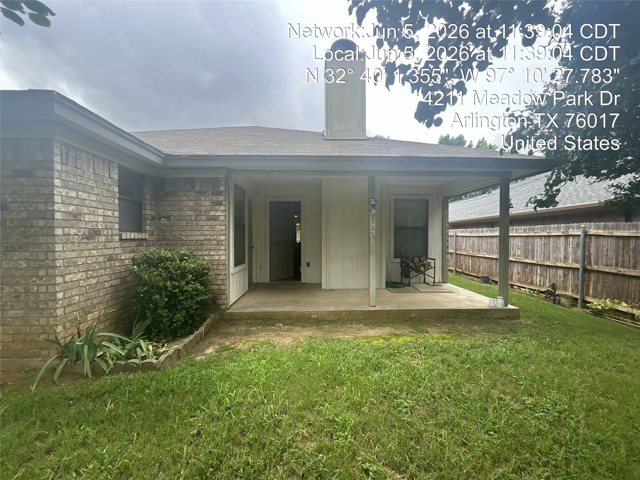 Rear patio featuring a covered concrete slab, brick exterior, and partial fencing