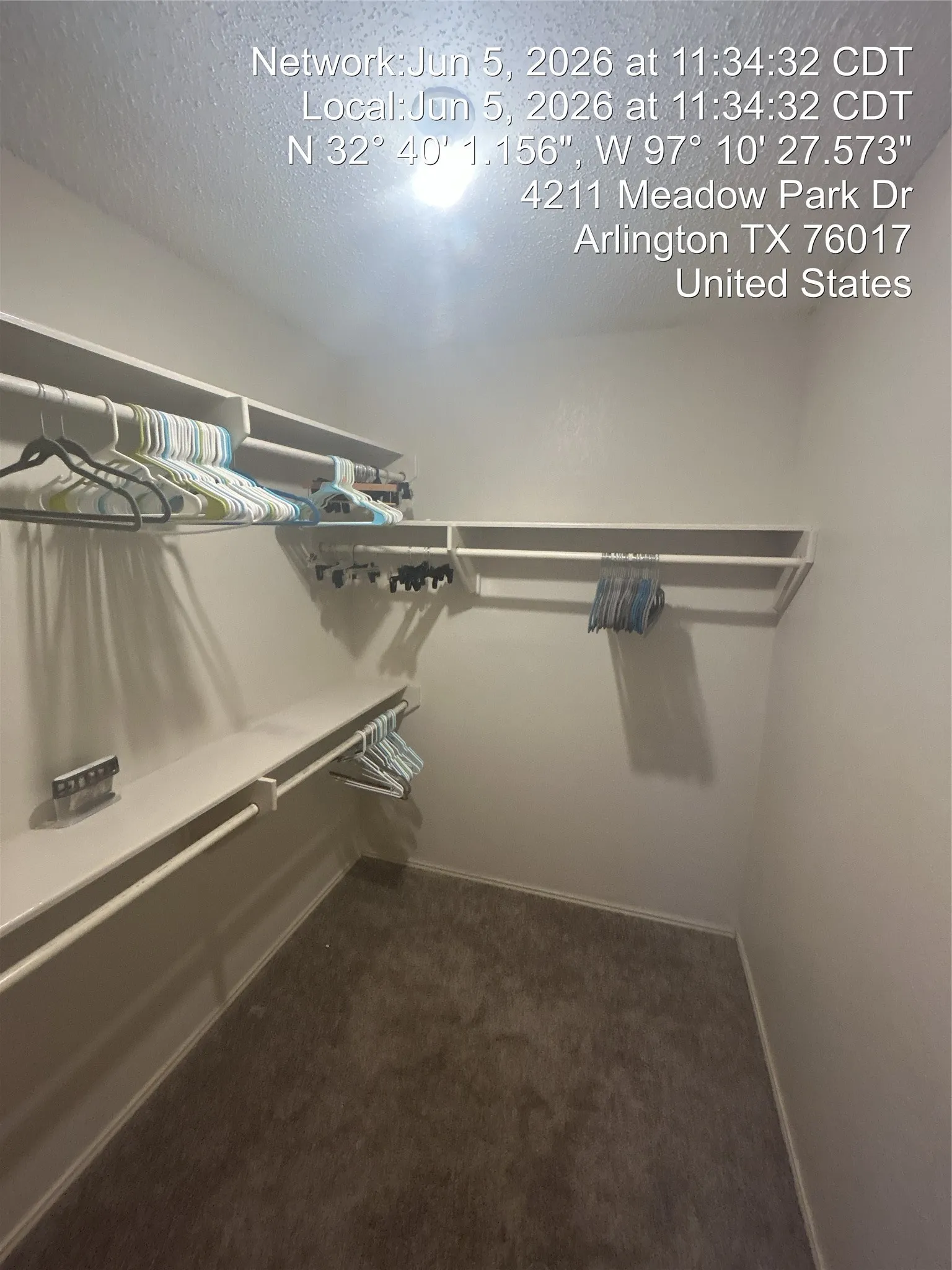 Walk-in closet featuring white walls, carpeted flooring, and built-in white shelving with hanging rods