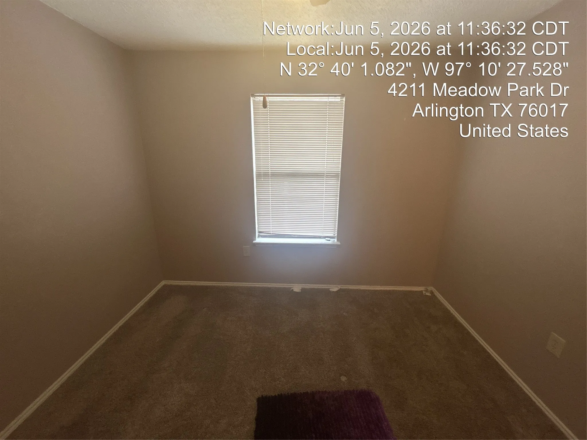 Neutral wall paint, carpet flooring, and a single window with blinds