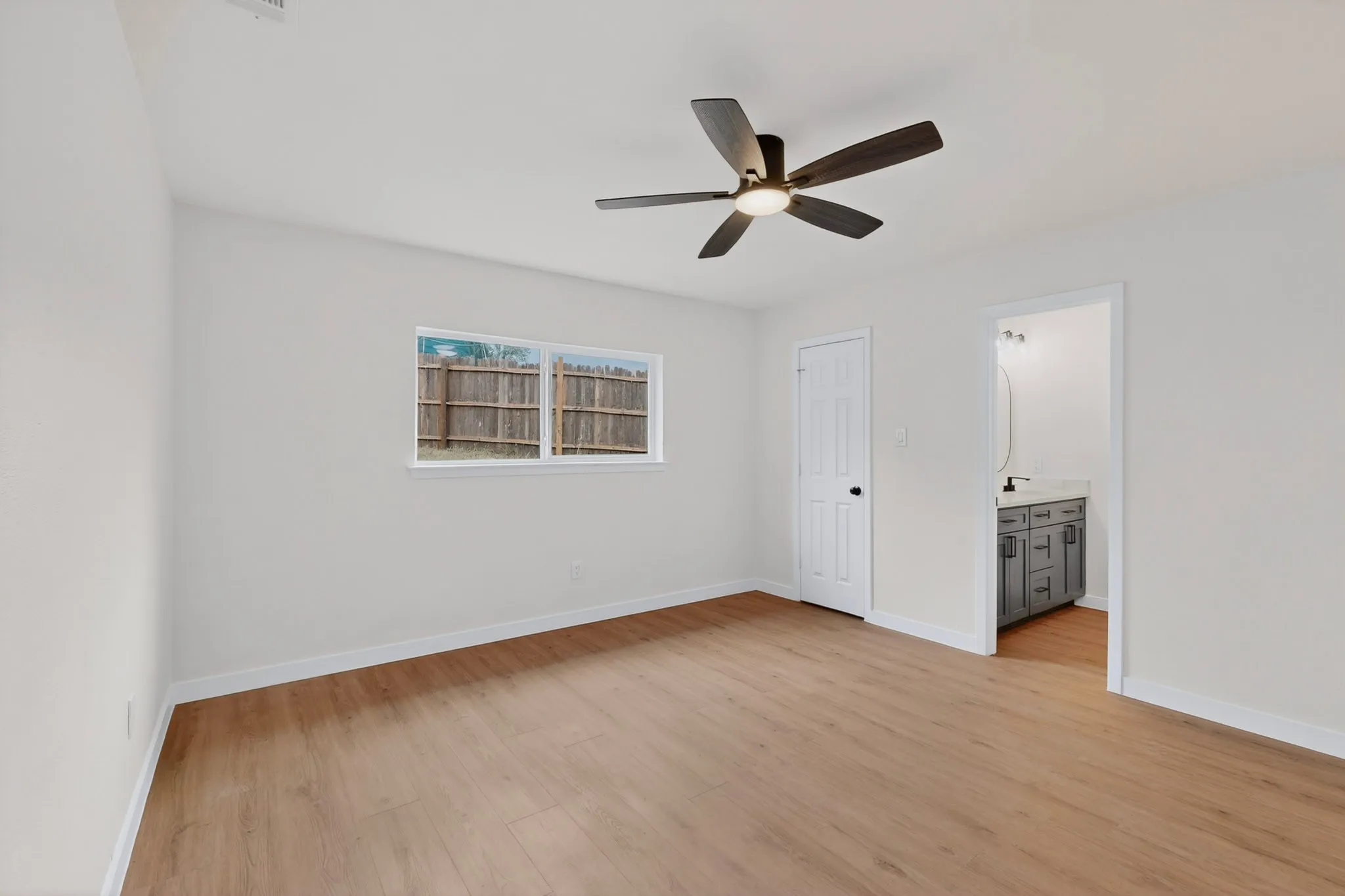Spacious room with wood-finish flooring, a contemporary ceiling fan, and a bright window
