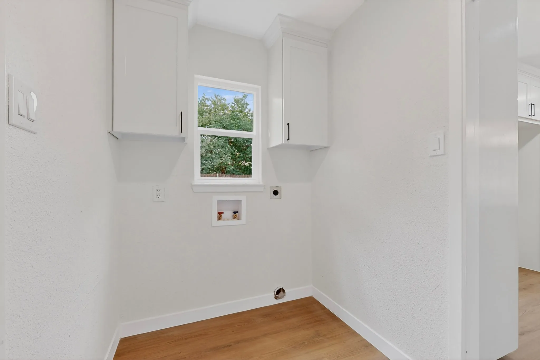 Utility space featuring a window, built-in cabinetry, and wood-finish flooring