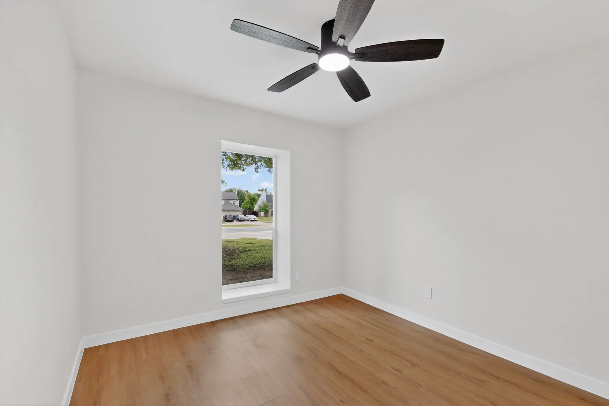 Room with wood-finish flooring, white baseboards, and light-colored walls
