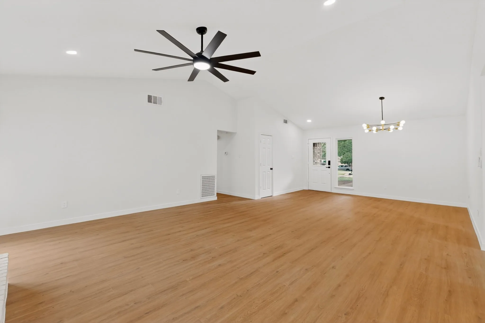 Spacious room featuring vaulted ceilings, wood-finish flooring, recessed lighting, and a modern ceiling fan