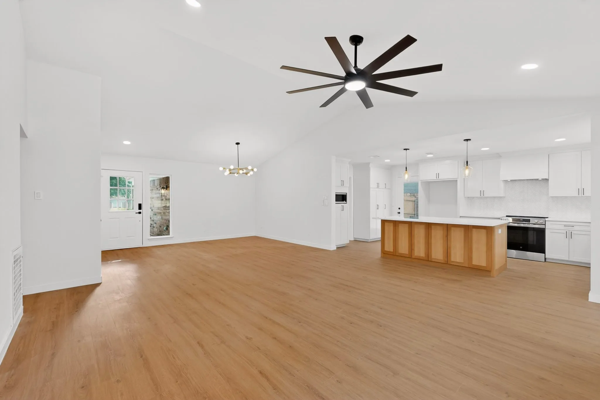Open-concept living space with vaulted ceilings, wood-finish flooring, a modern ceiling fan, and recessed lighting