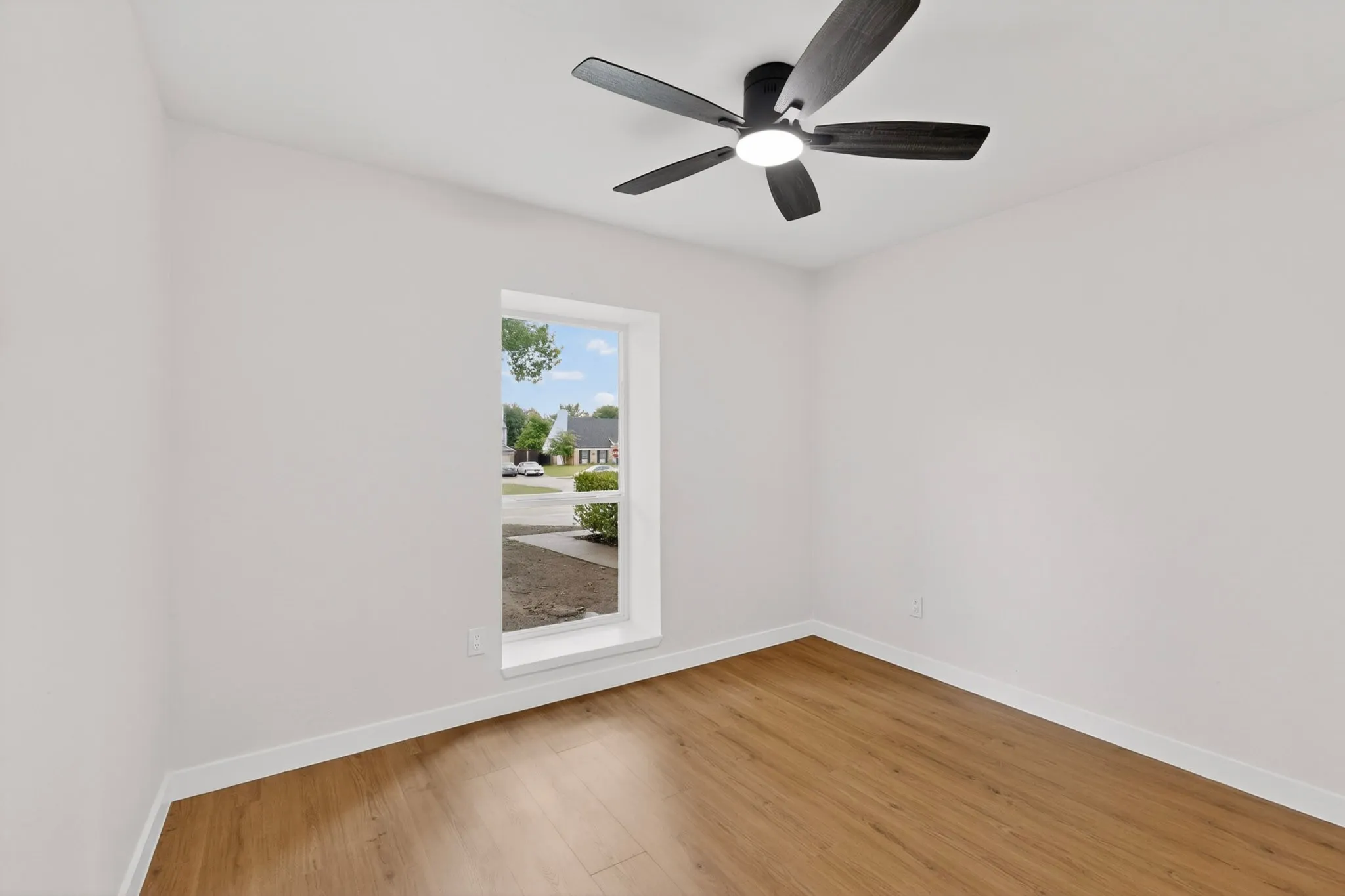 Bright interior space with wood-finish flooring and a contemporary ceiling fan with integrated lighting