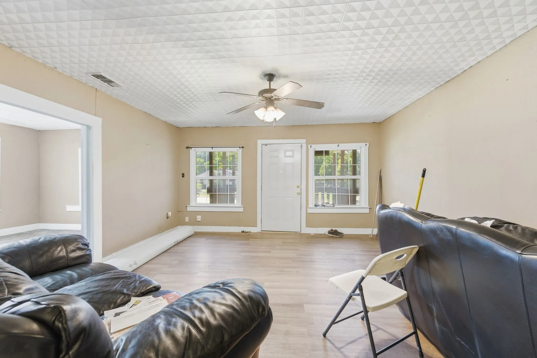 Living area featuring wood-finish flooring, a textured ceiling, a ceiling fan with integrated lighting, and multiple windows