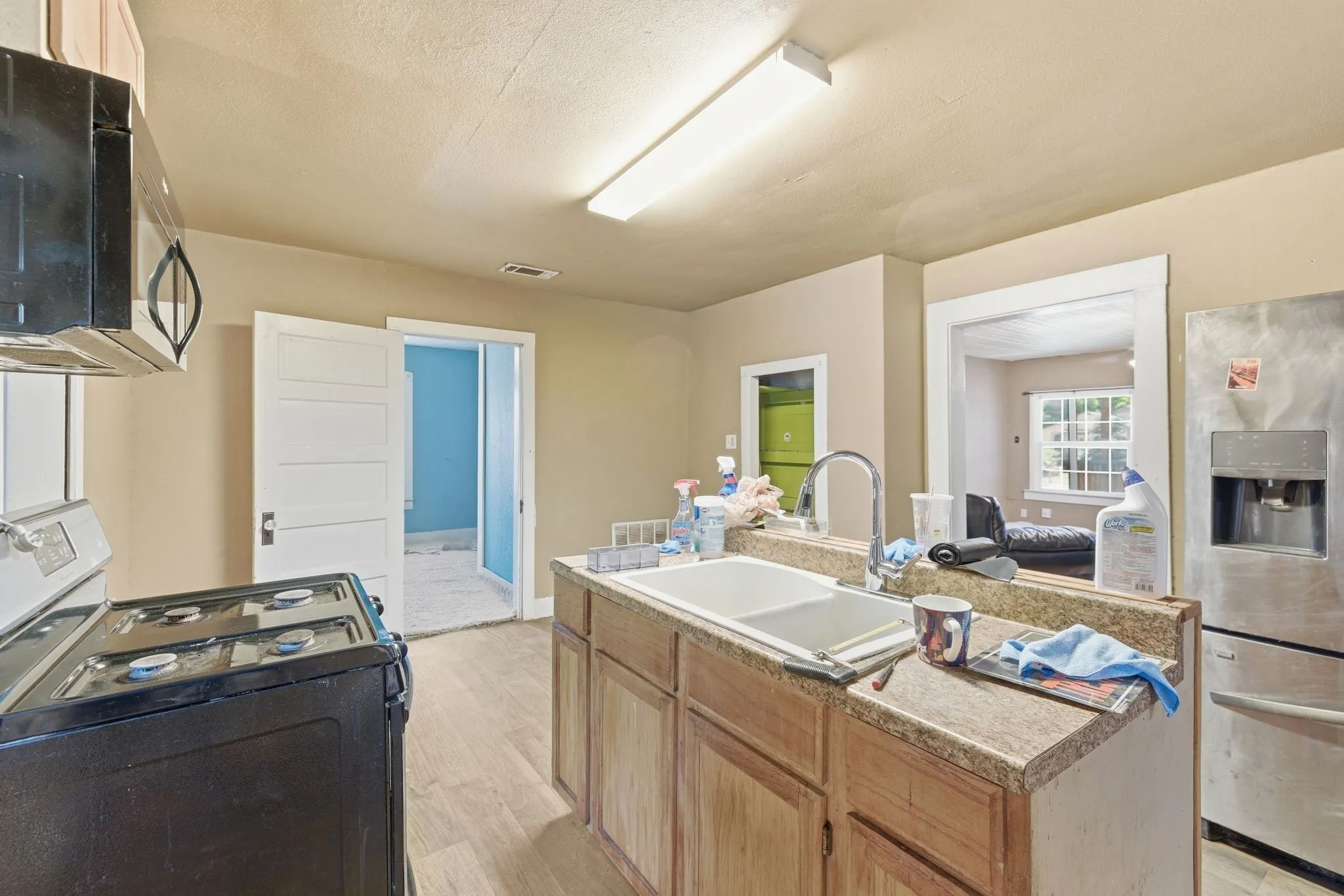 Kitchen featuring wood-finish flooring, stainless steel refrigerator, black range with overhead microwave, and a double basin sink with a chrome faucet