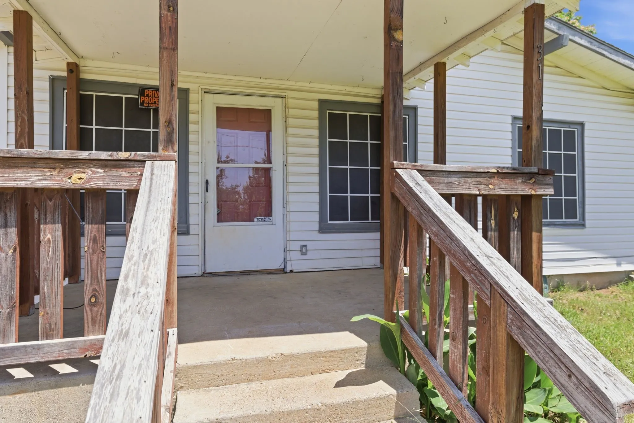 Front porch entry featuring concrete steps and a wood railing system