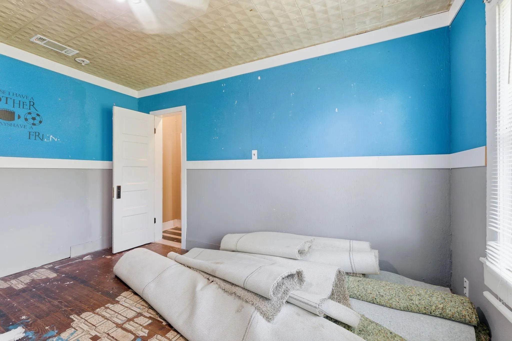 Room with two-tone wall treatment, textured ceiling, original wood flooring, and a white paneled door