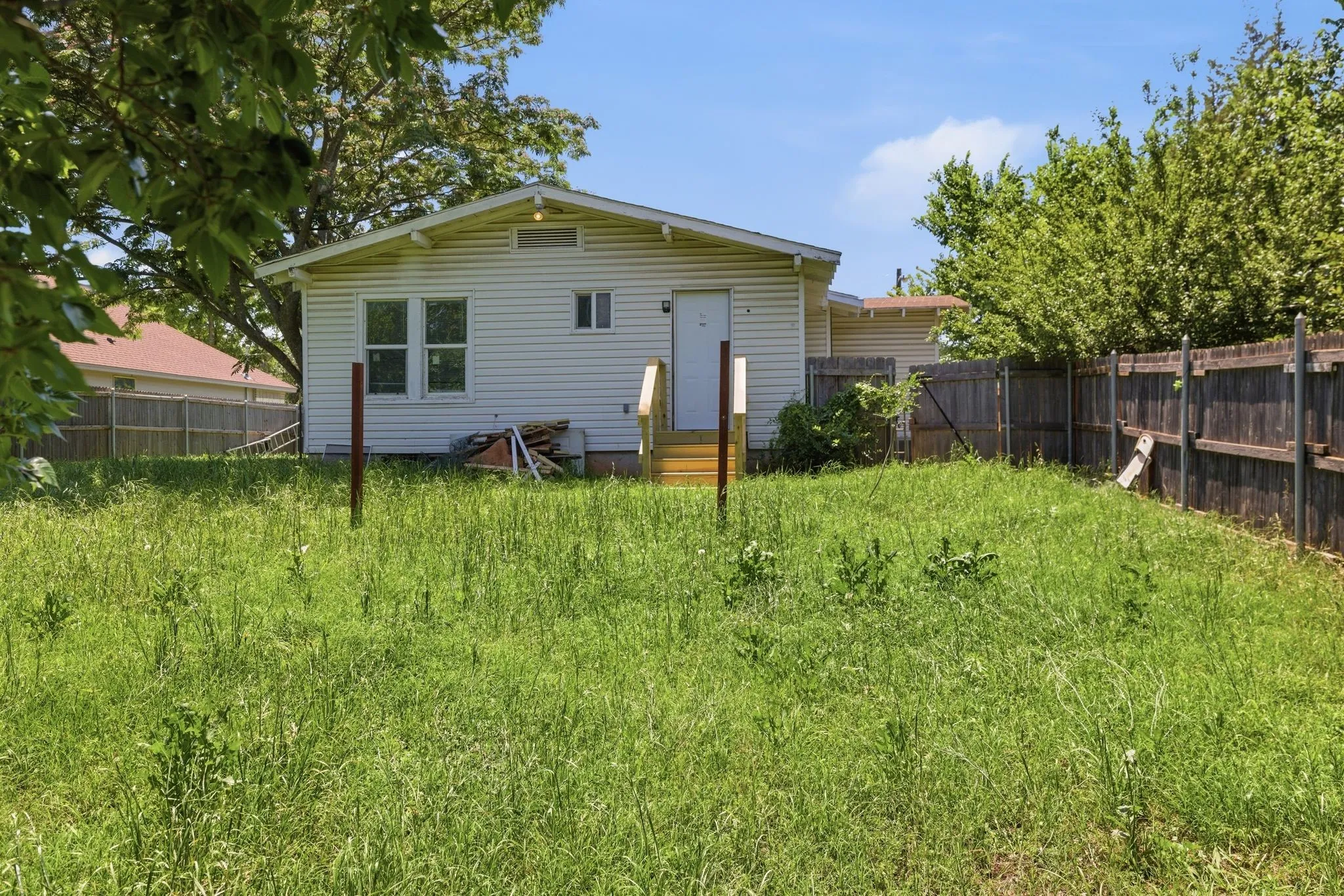 Rear exterior featuring horizontal siding, a wood-finish deck with railings, and a fenced perimeter