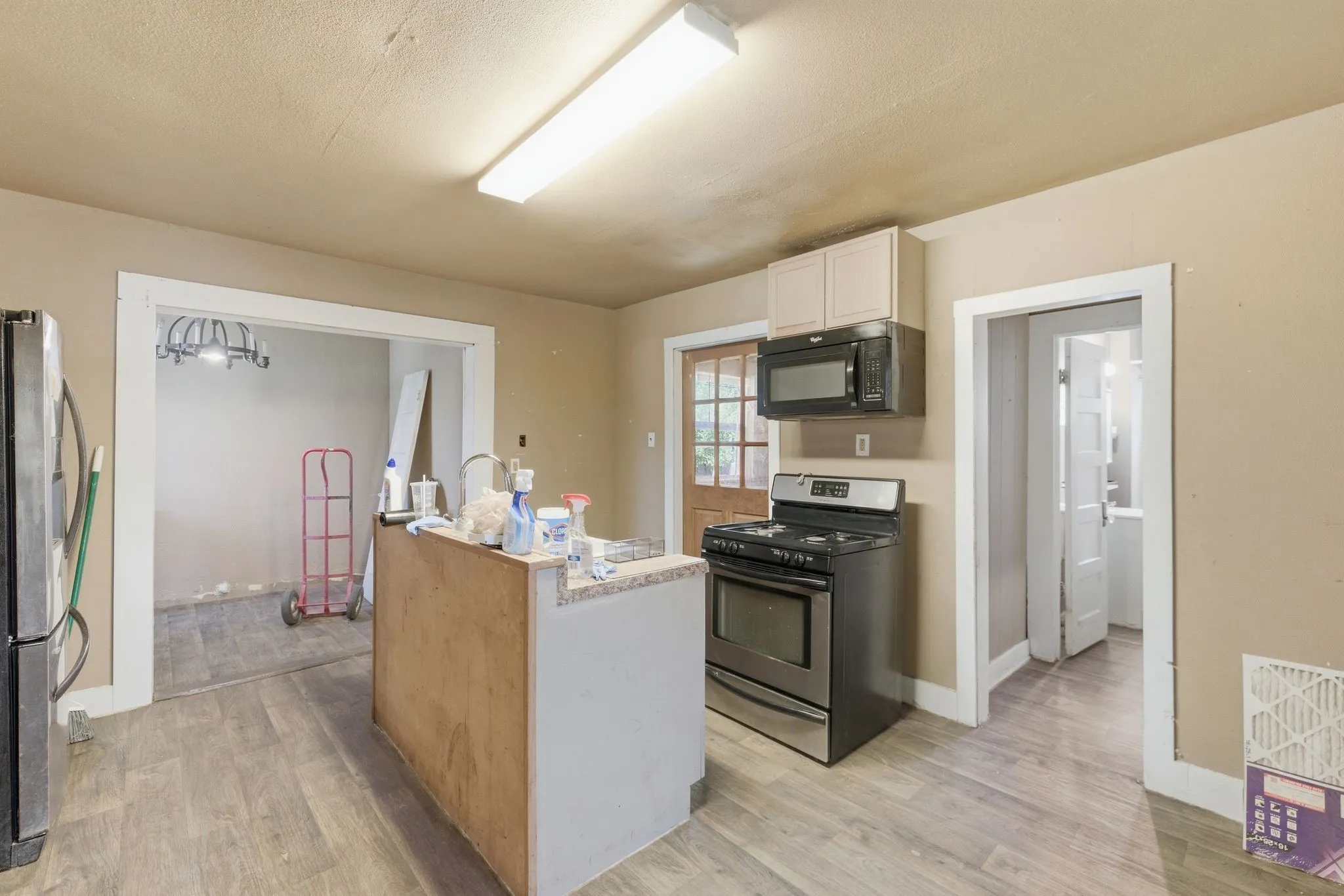 Kitchen featuring wood-finish flooring, a central island with a sink, stainless steel range, and a built-in microwave