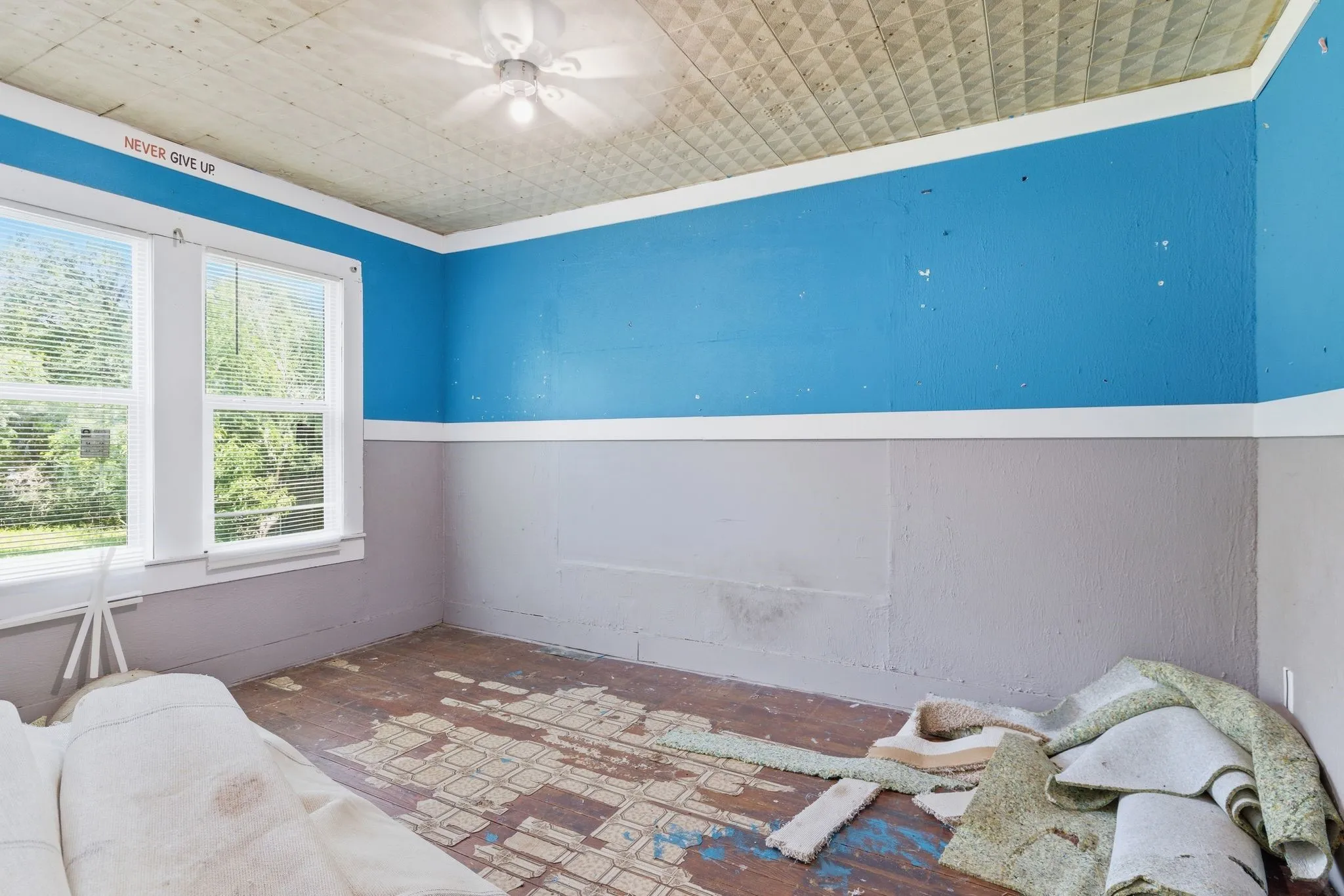 Room featuring two large windows, a textured ceiling with a ceiling fan, and a two-toned wall treatment