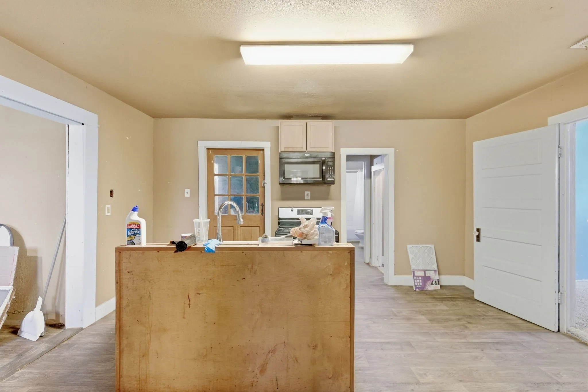 Central island with sink, wood-finish flooring, and multiple doorways providing access to other rooms