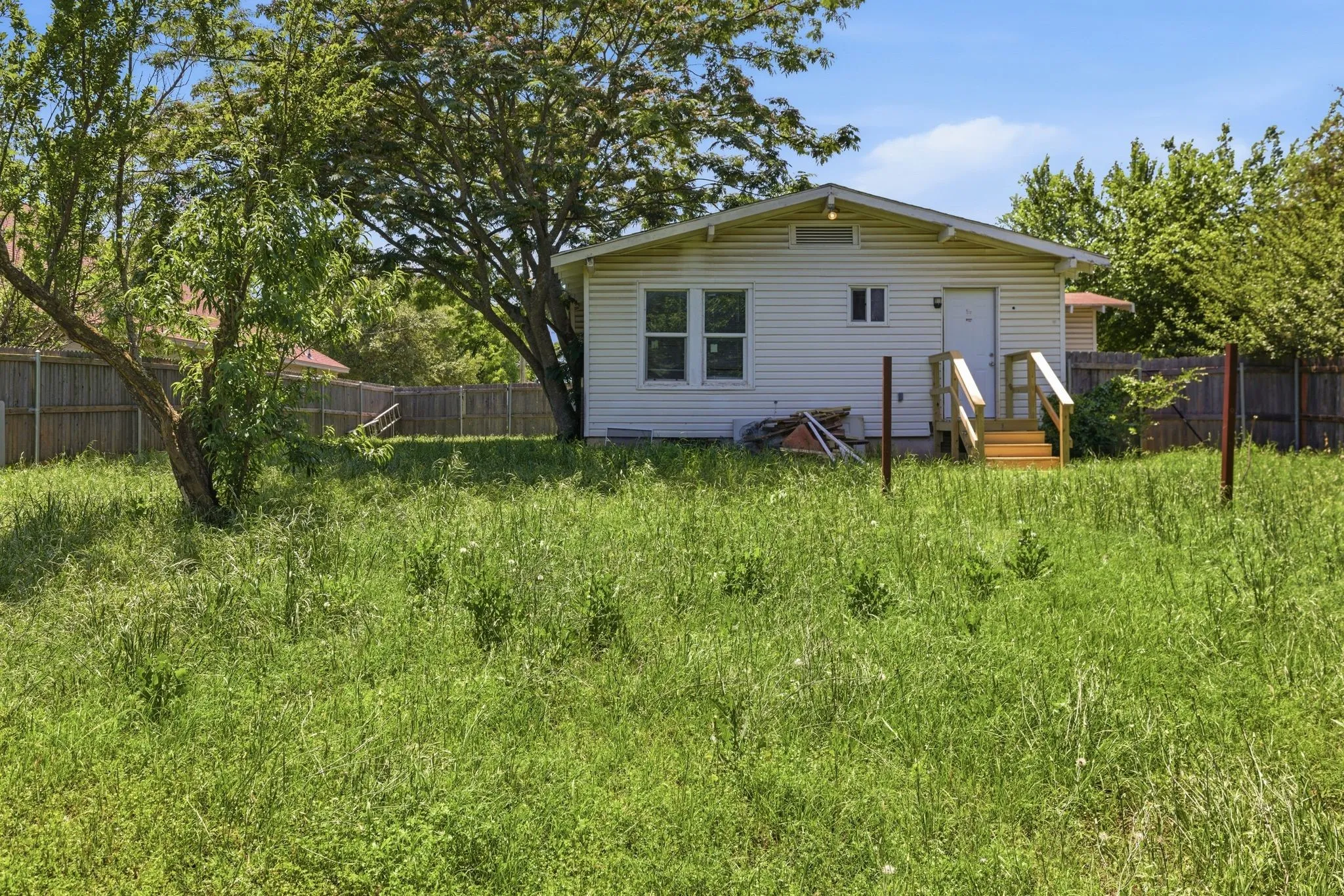 Rear exterior featuring white vinyl siding, a gabled roofline, and a newly constructed wooden deck and stairs