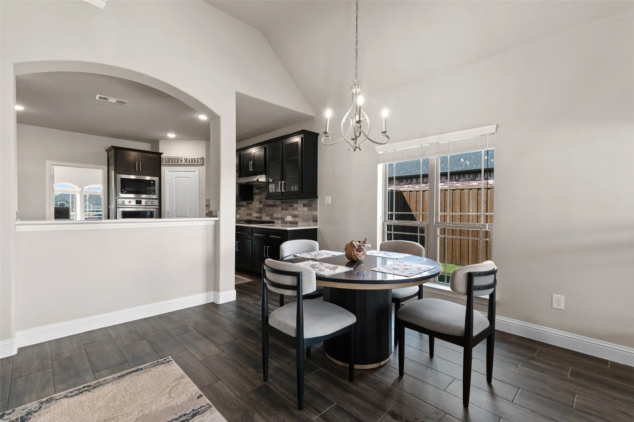 Dining area featuring wood-finish flooring, a contemporary chandelier, and a large window