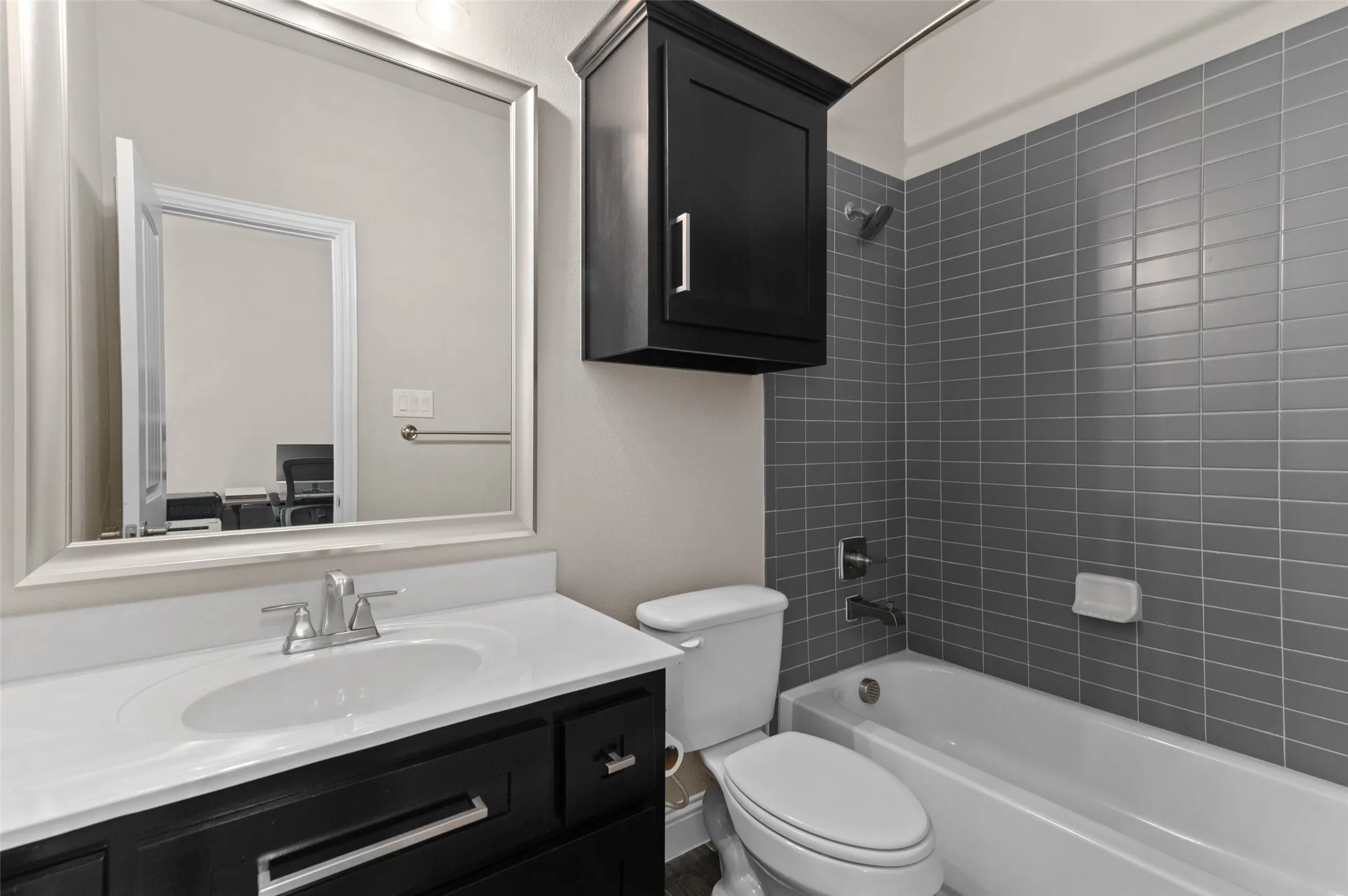 Bathroom featuring a dark wood-finish vanity with a white countertop, chrome fixtures, and a framed mirror