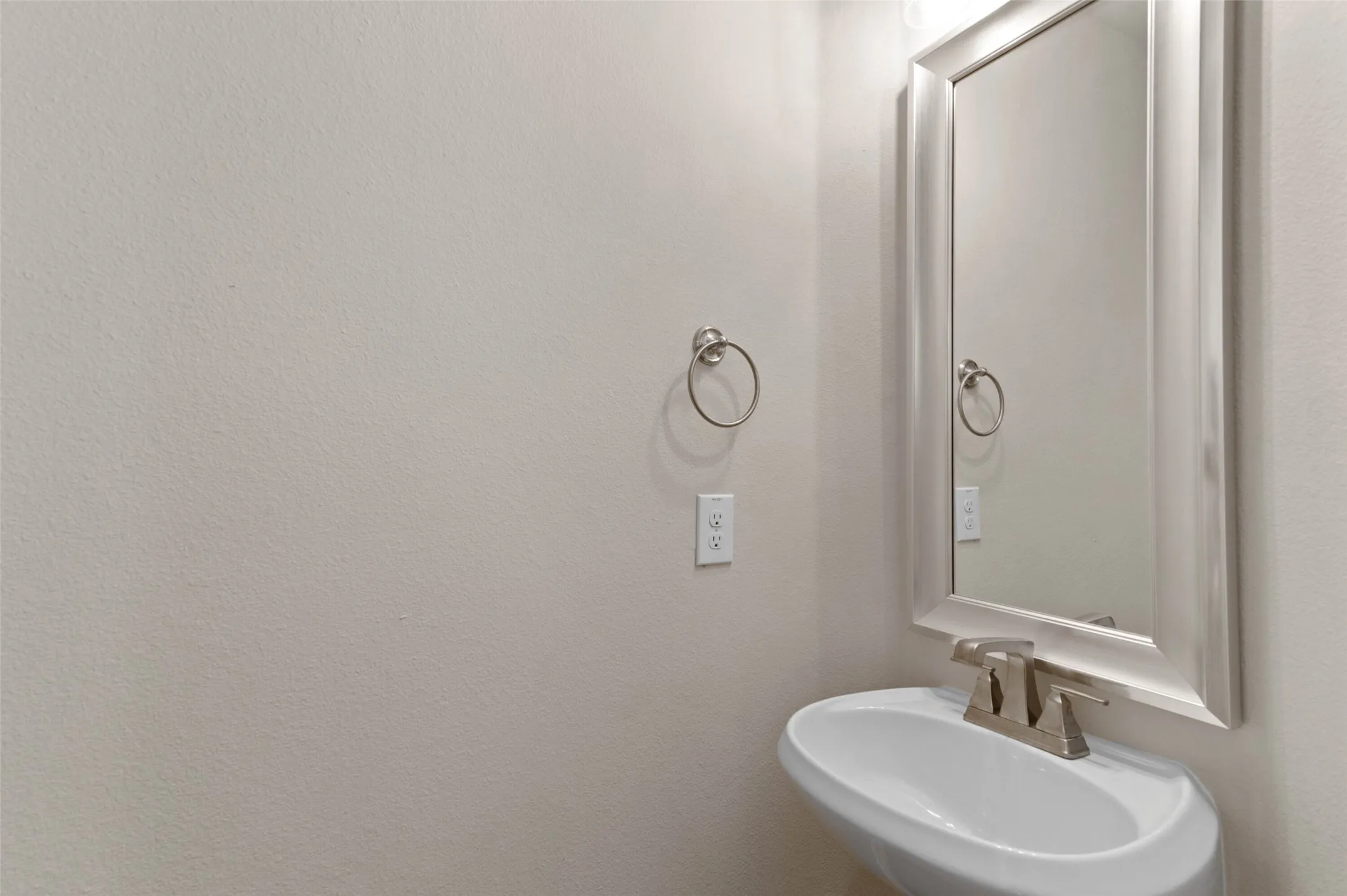 Half Bath upstairs with Pedestal sink with a two-handle faucet, framed mirror, and a wall-mounted towel ring