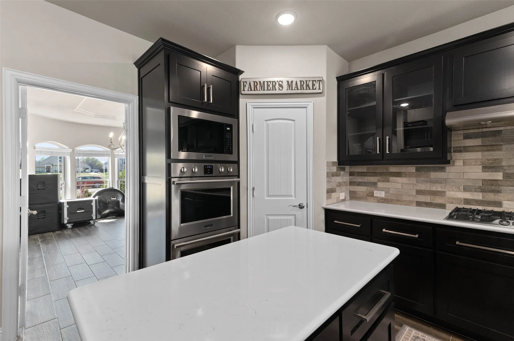 Gourmet kitchen featuring dark wood cabinetry, stainless steel appliances, a white island countertop, and a tiled backsplash