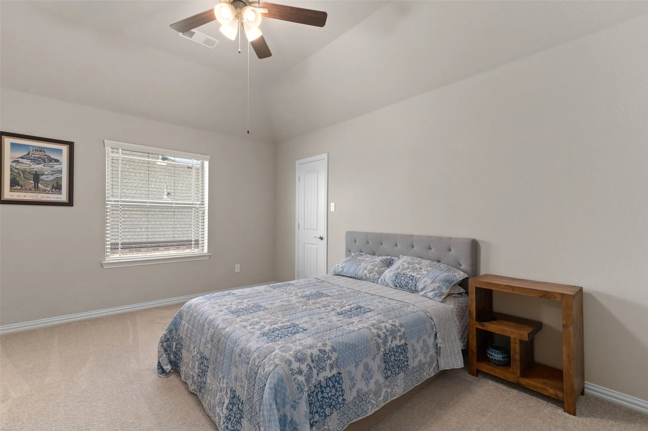 Carpeted room featuring a vaulted ceiling with a ceiling fan, a window with horizontal blinds, and a white interior door
