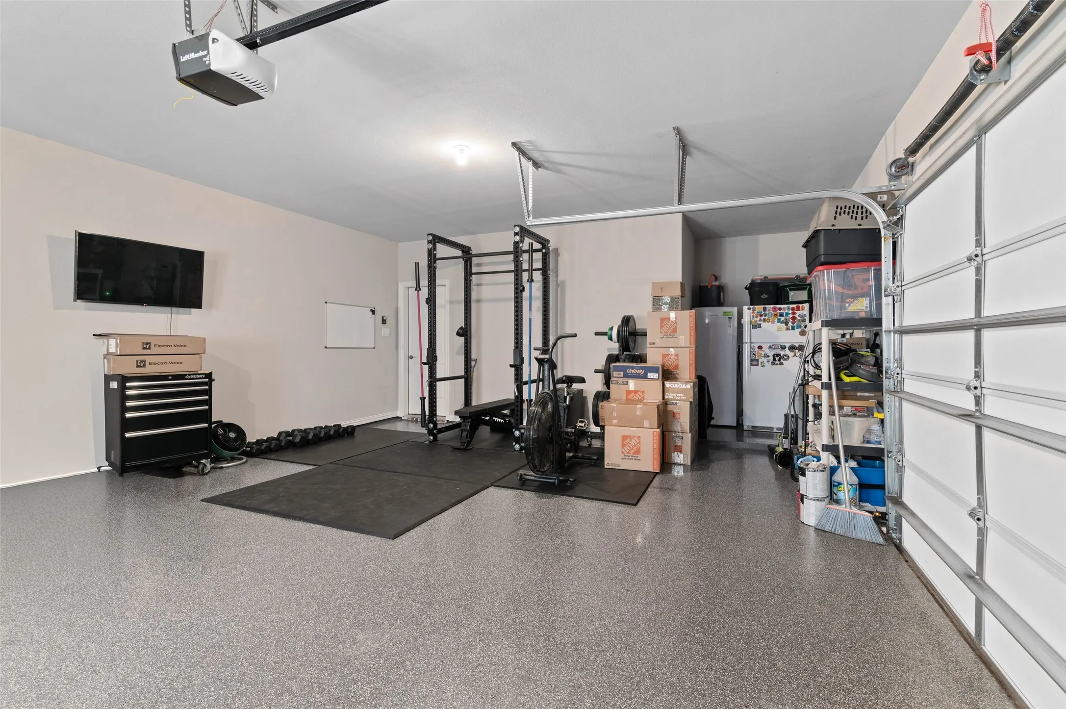 Garage with light gray epoxy flooring and an overhead door opener mechanism