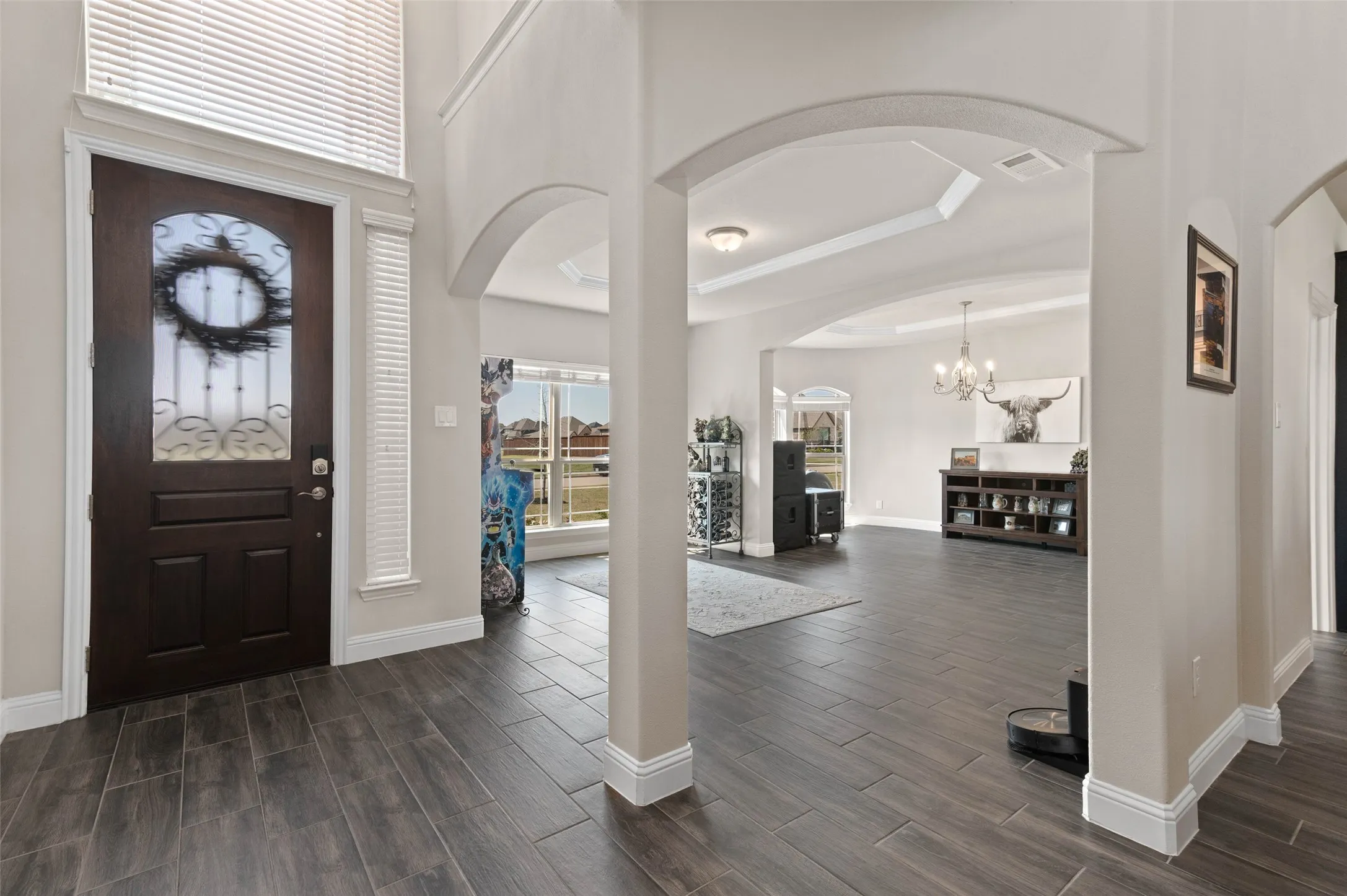 Grand entry foyer featuring wood-finish tile flooring, a dark wood entry door with ornate glass detailing!