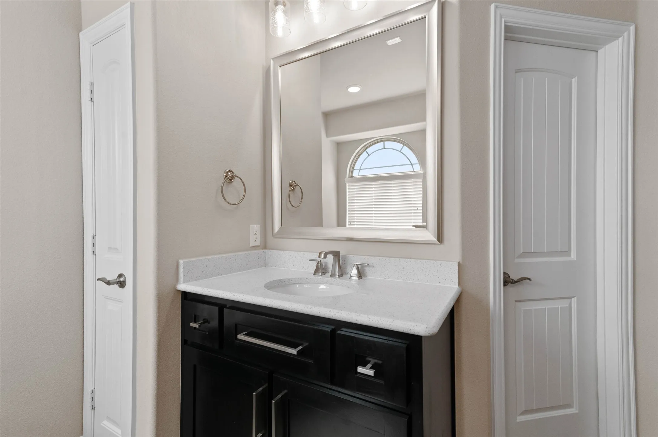 Bathroom vanity featuring a dark wood-finish cabinet with silver hardware, an integrated white sink, and a light-colored countertop
