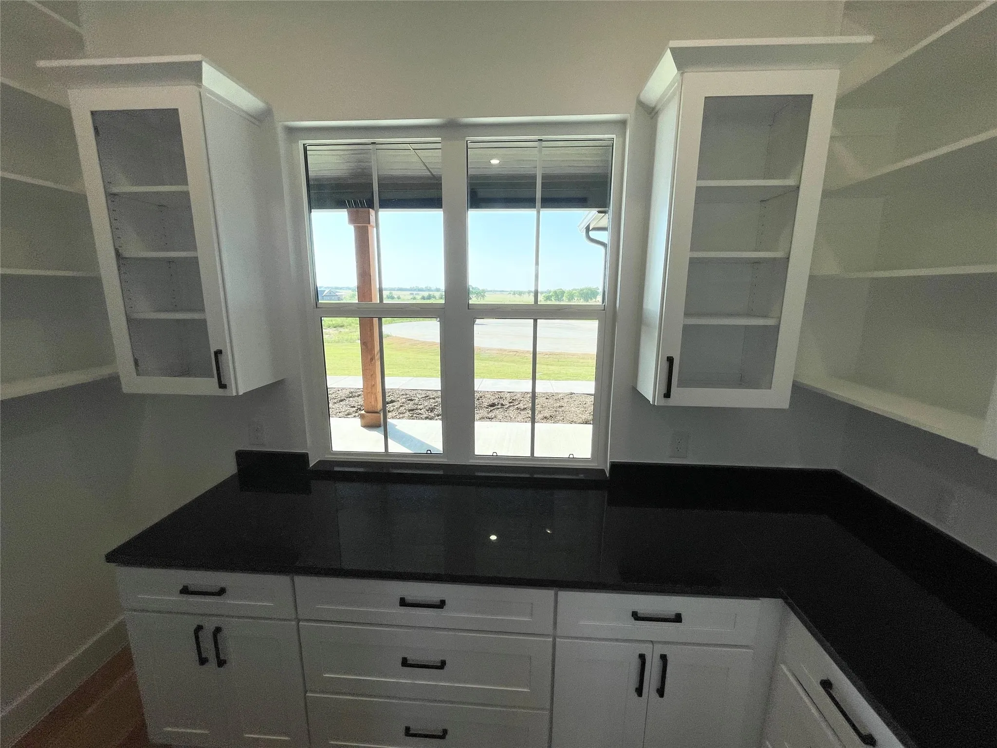 White cabinetry with dark hardware, dark countertops, and a window