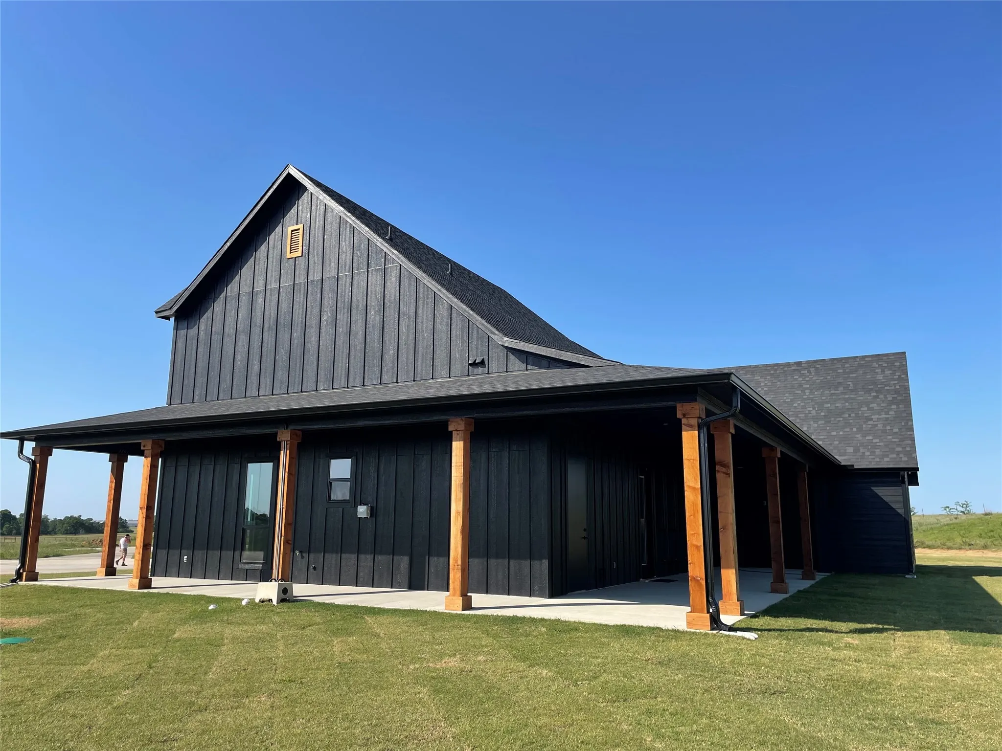 Modern farmhouse-style exterior featuring dark vertical siding and a steeply pitched shingle roof
