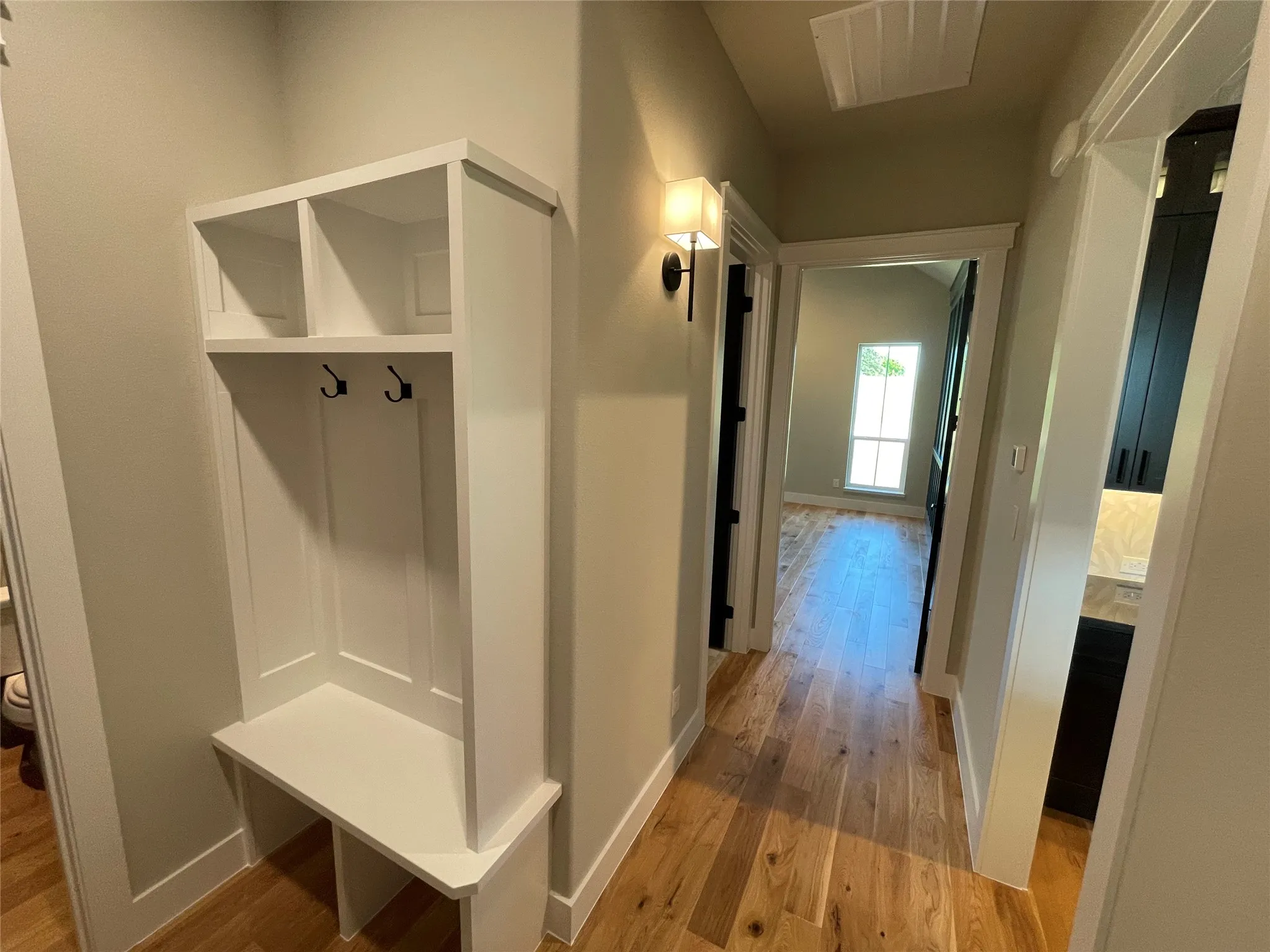 Entryway mudroom featuring a built-in white storage bench with upper cubbies and coat hooks