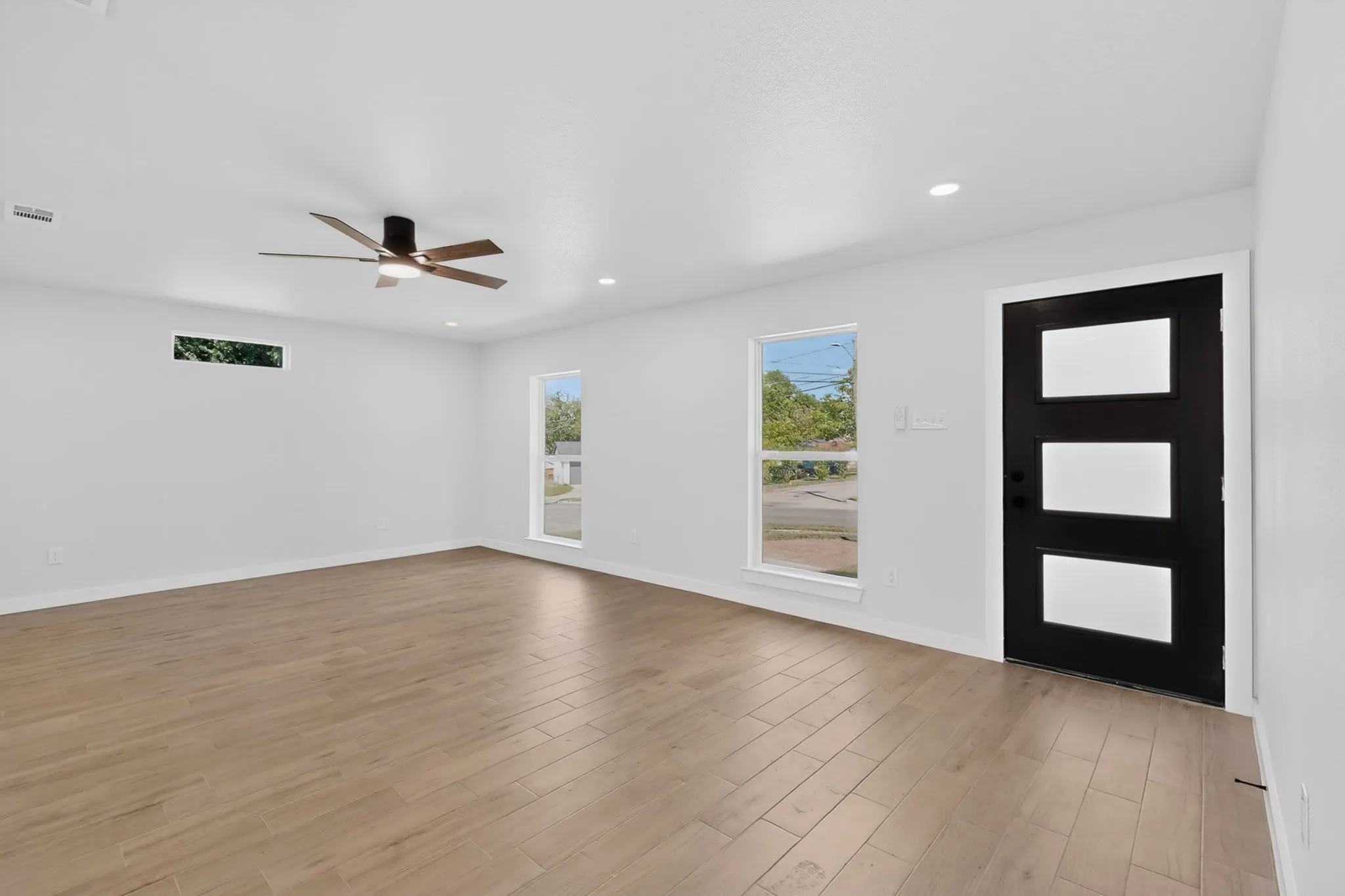 Spacious interior with wood-finish flooring, white walls, and recessed lighting