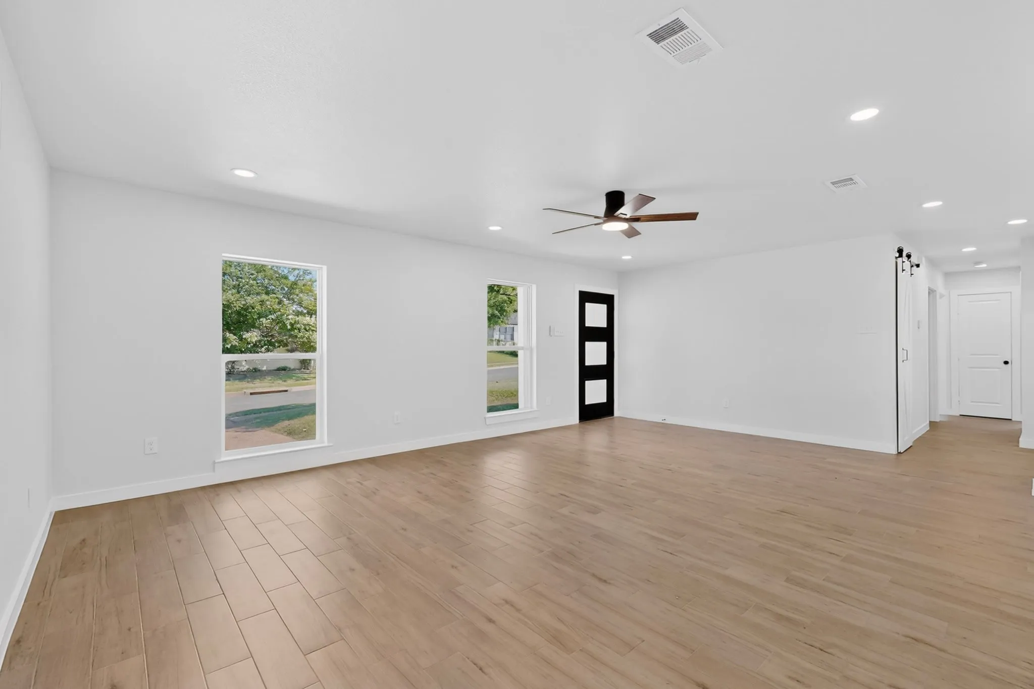 Spacious interior featuring wood-finish flooring, recessed lighting, and a contemporary ceiling fan
