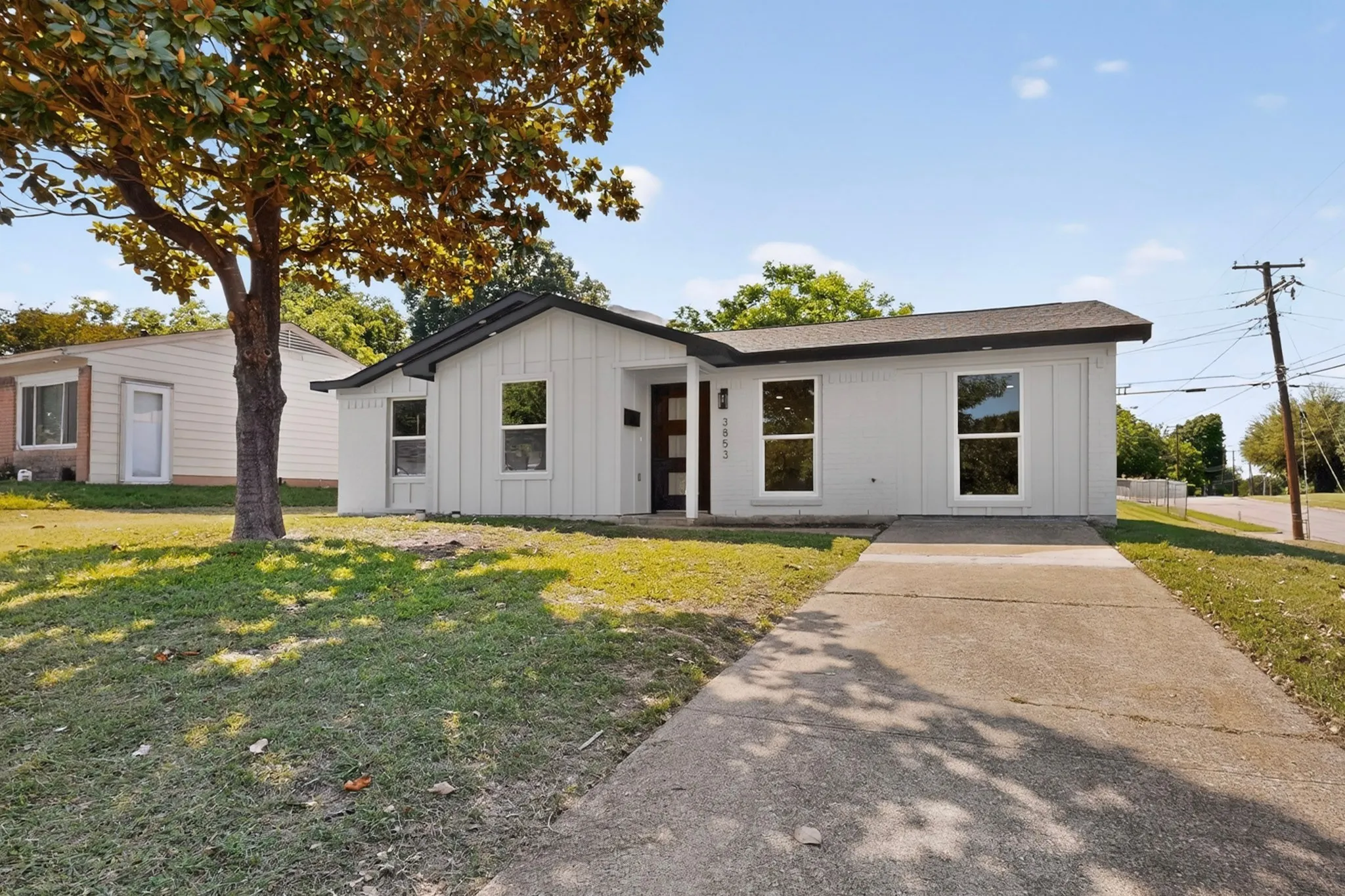 Modern ranch-style home featuring a light gray exterior, dark trim, and a black front door