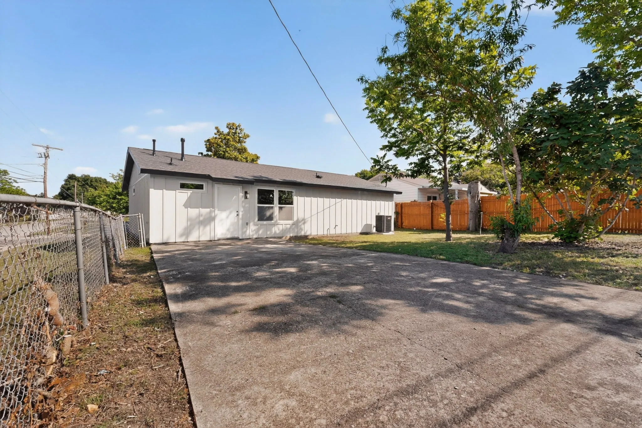 Single-story residence featuring a gray exterior with vertical paneling, a dark shingle roof, and multiple windows