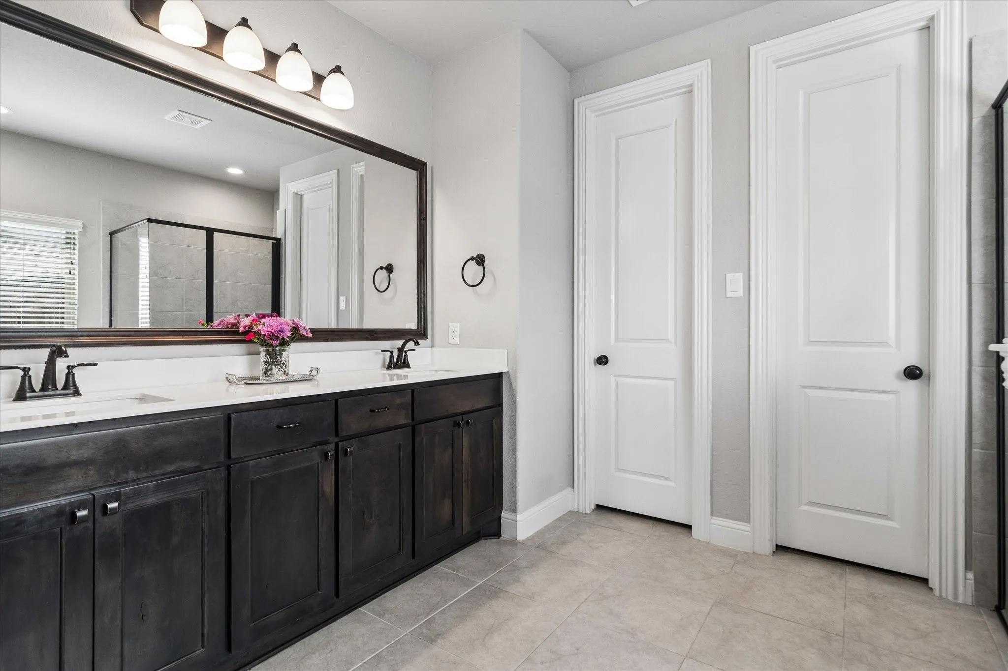 Dual-sink vanity with dark wood-finish cabinetry, spacious counter tops and rectangular undermount sinks