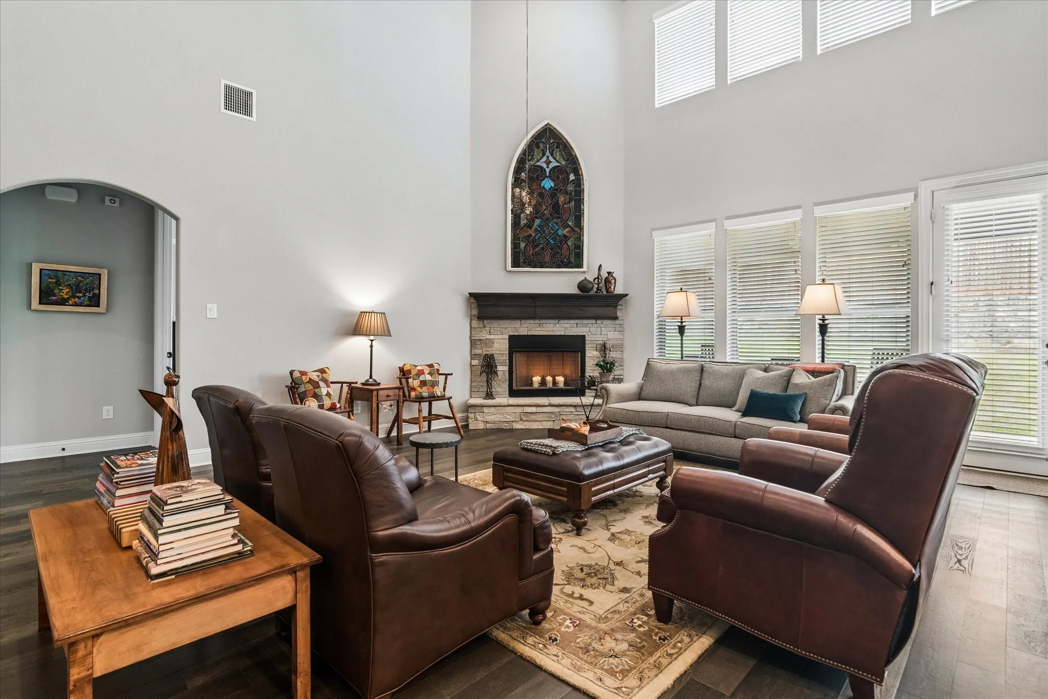 Soaring vaulted ceiling living space with a stone-clad fireplace and dark wood-finish flooring