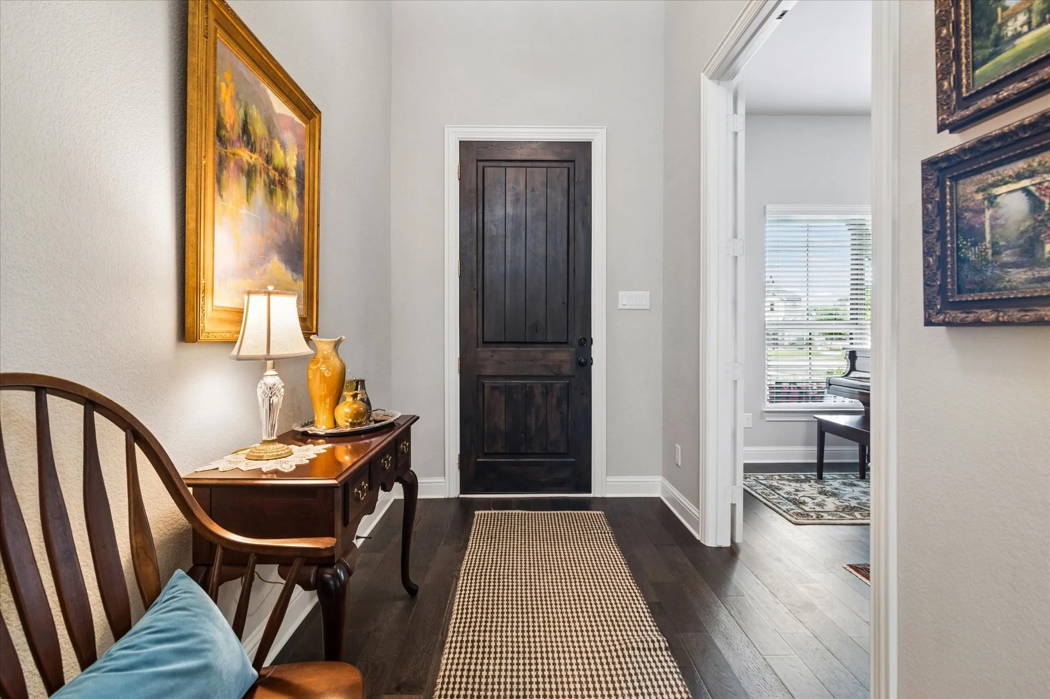 Entryway into the home with dark wood-finish flooring and access to the fifth bedroom.