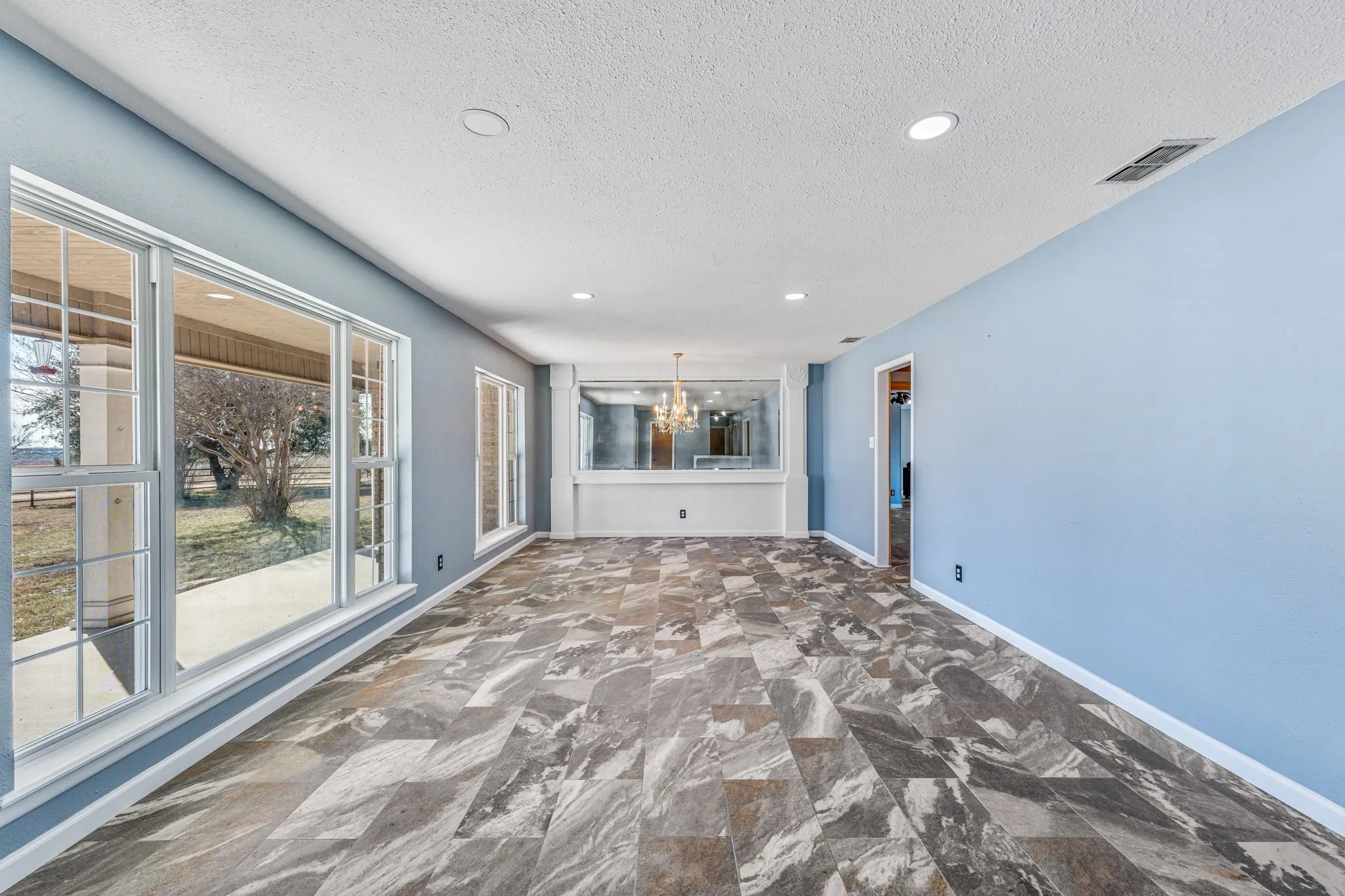 Spacious room featuring large windows, wood-finish flooring, recessed lighting, and a built-in mirrored wall accent