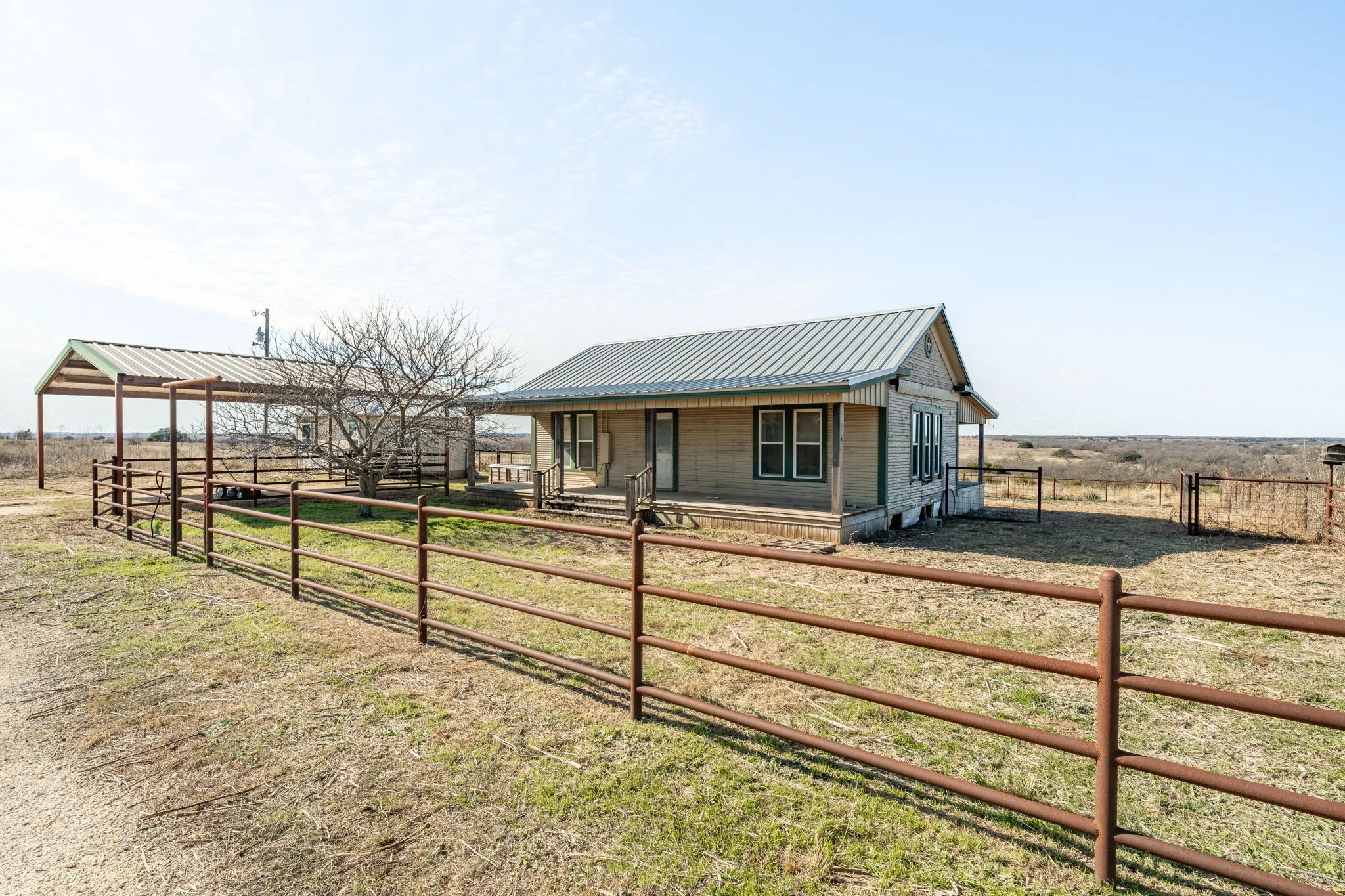 Ranch-style home featuring a metal roof, a covered front porch, and a dedicated covered structure
