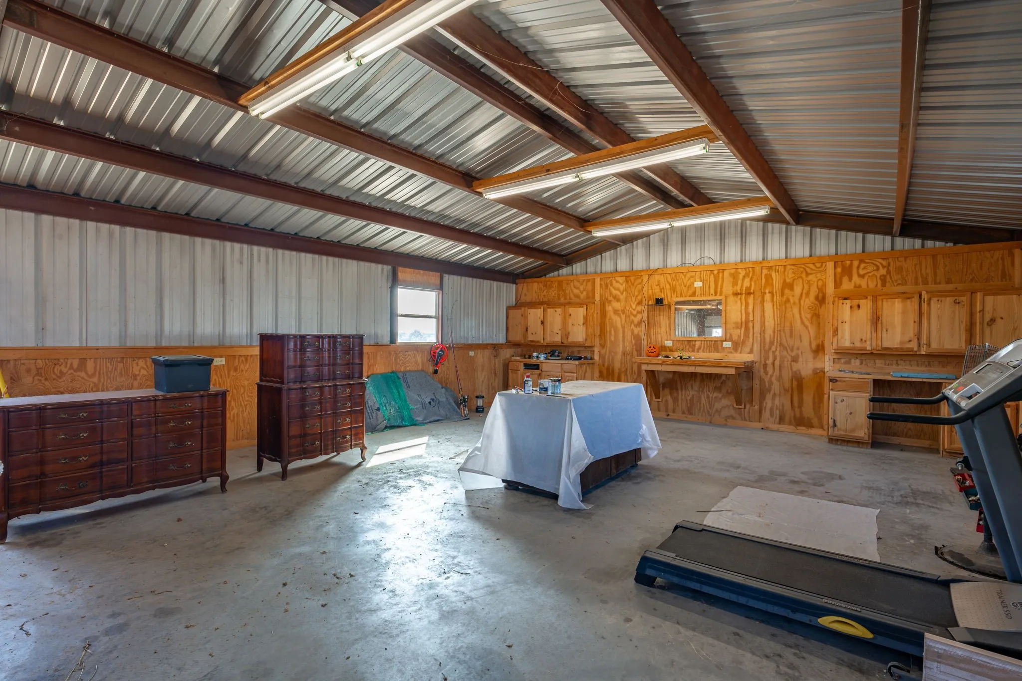 Spacious interior featuring a concrete floor, corrugated metal ceiling, and exposed metal beams