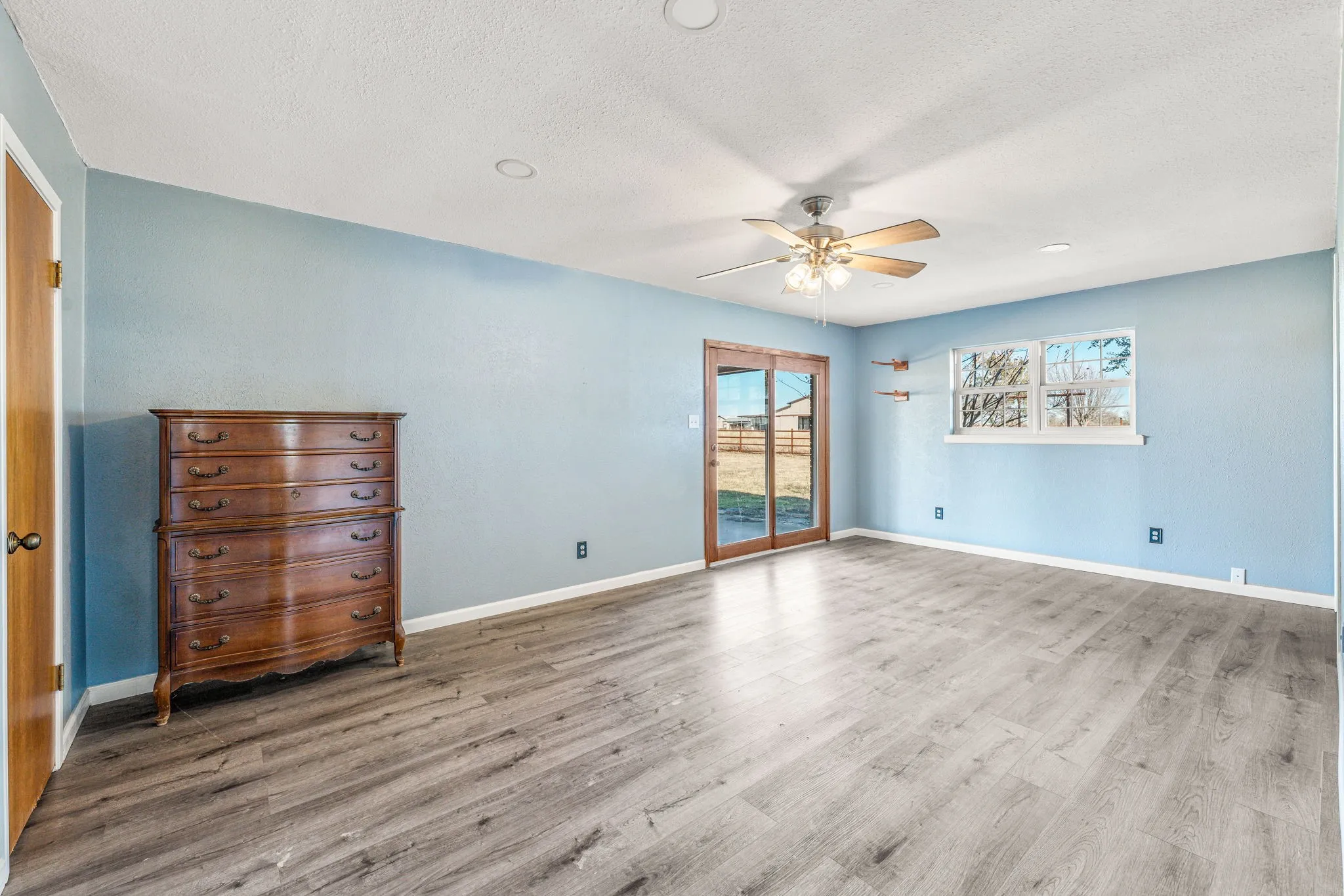 Spacious room with wood-finish flooring, light blue walls, and a white ceiling