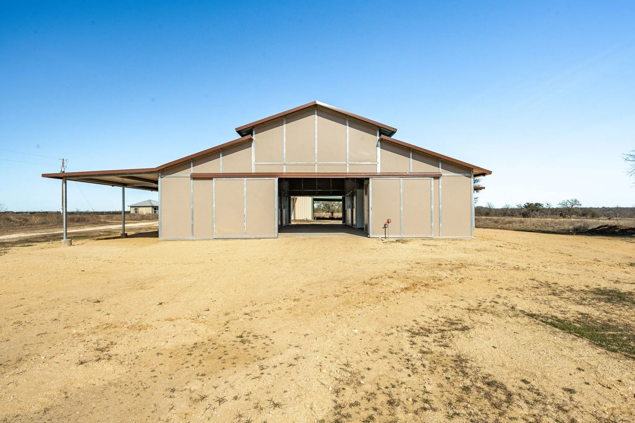 Spacious metal barn with a gabled roof, tan siding, and brown trim