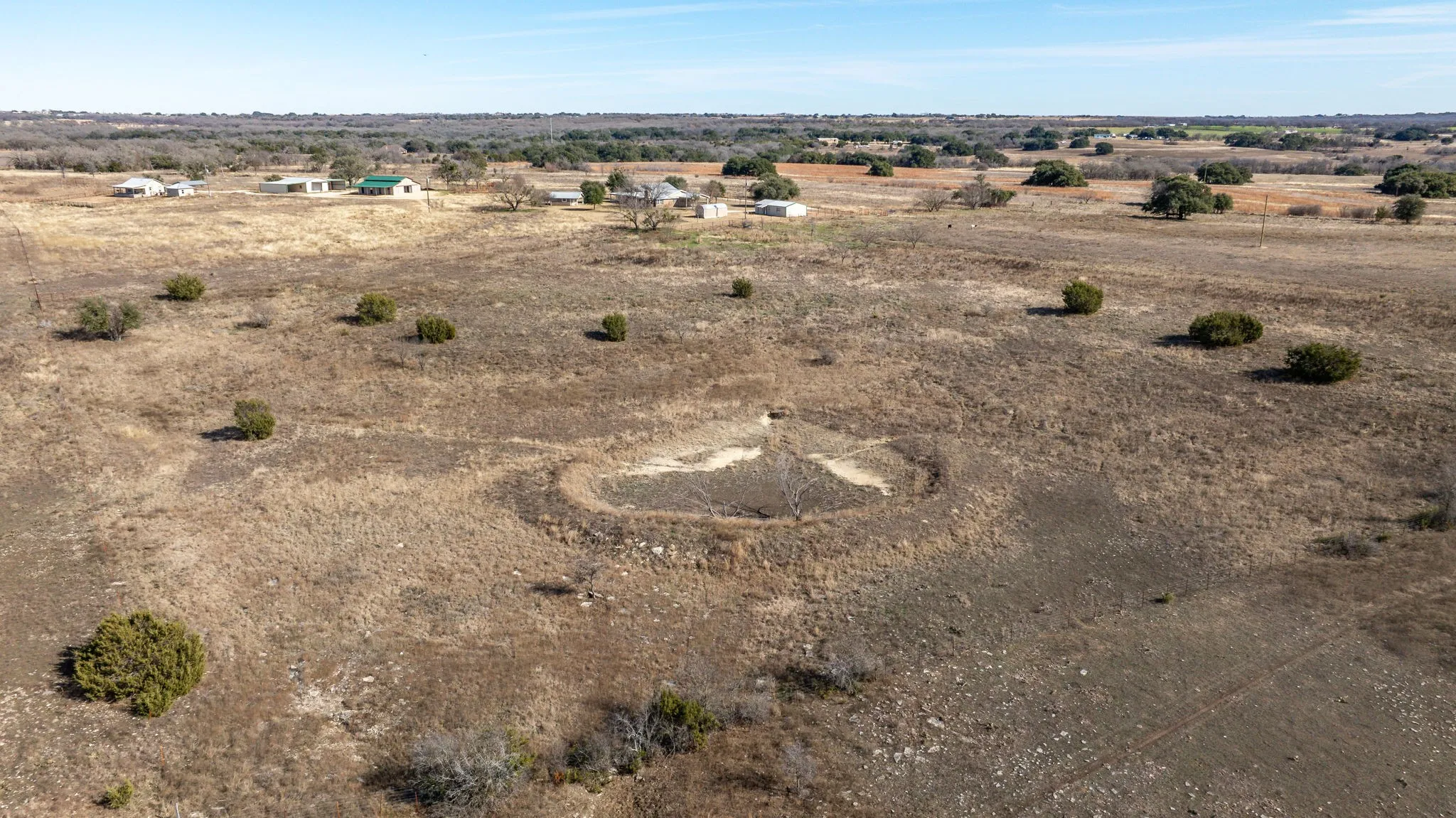 Expansive open land featuring sparse native brush and a defined depression