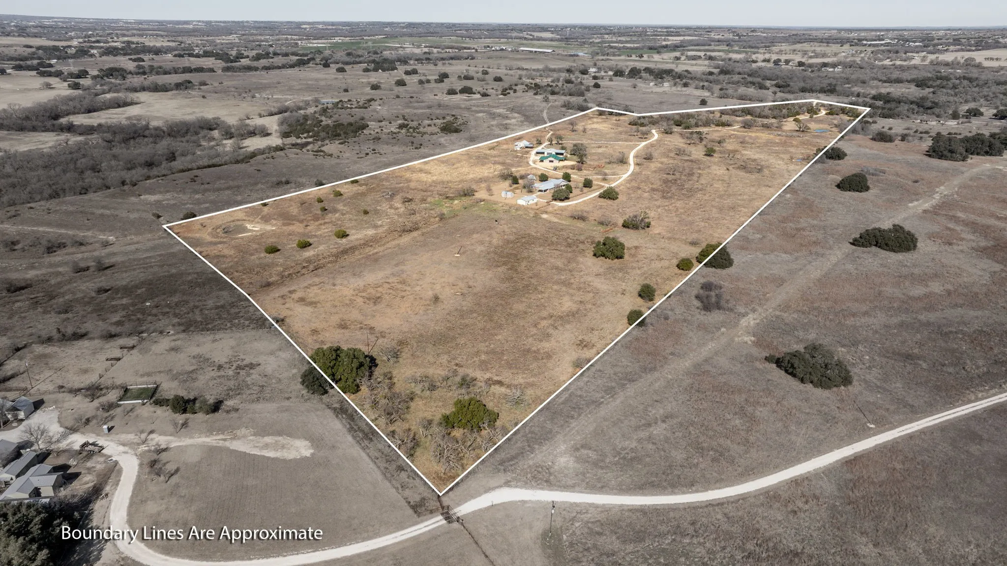 Expansive undeveloped land featuring a long winding driveway, multiple structures, and a swimming pool