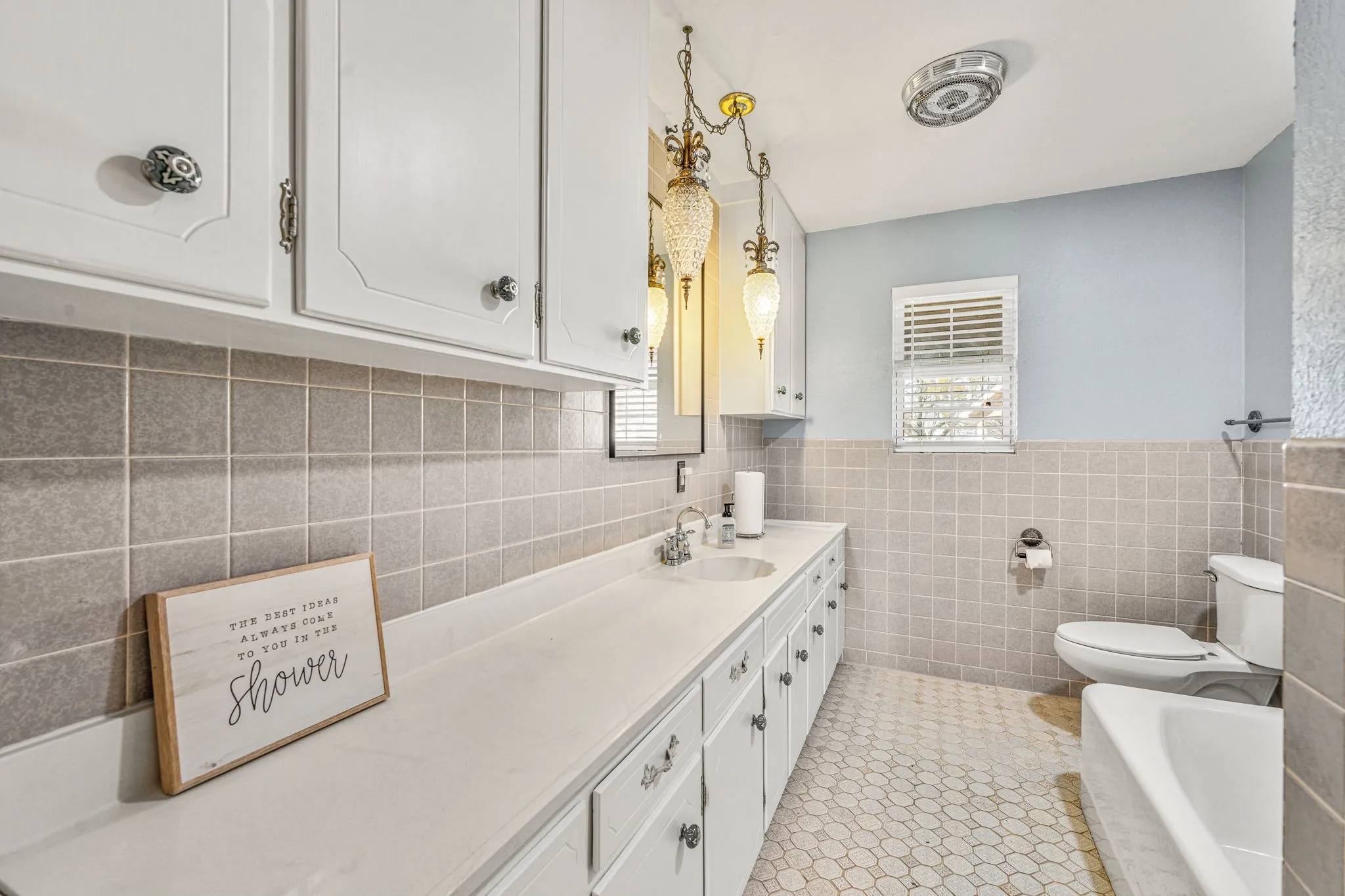 Bathroom featuring a white vanity with extensive counter space and under-sink cabinetry