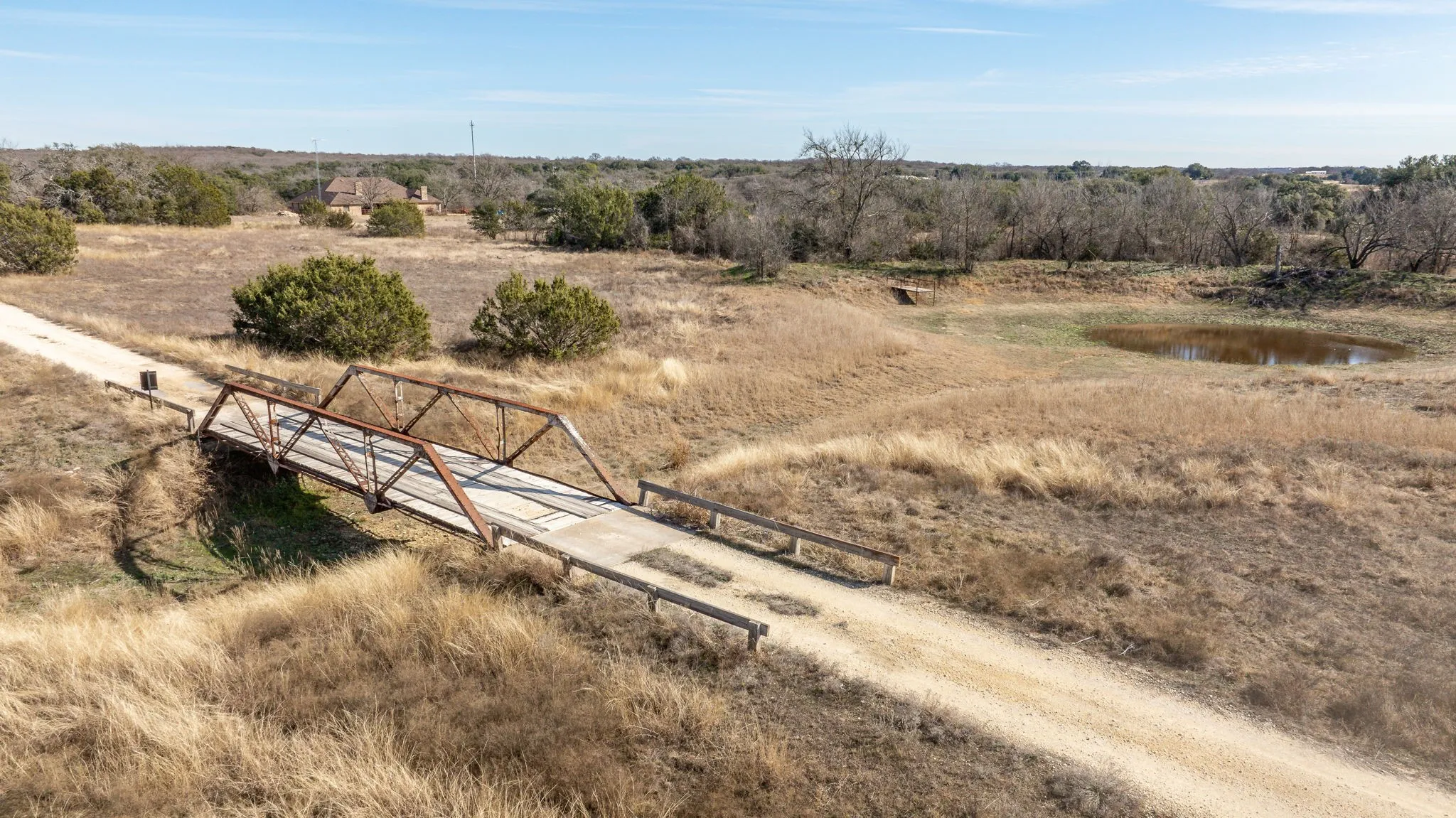 Gravel road featuring a metal truss bridge and natural landscape