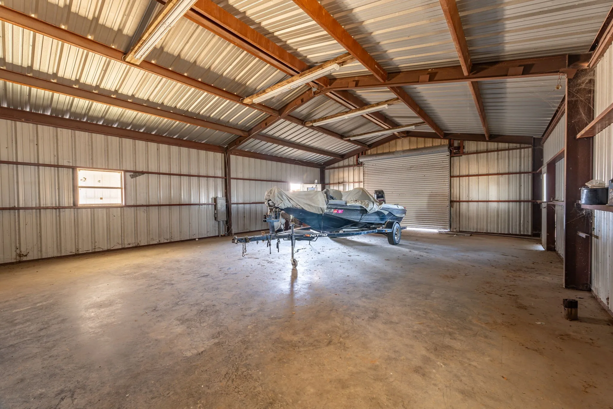 Spacious metal-frame building featuring a concrete floor, corrugated metal walls, and an overhead door