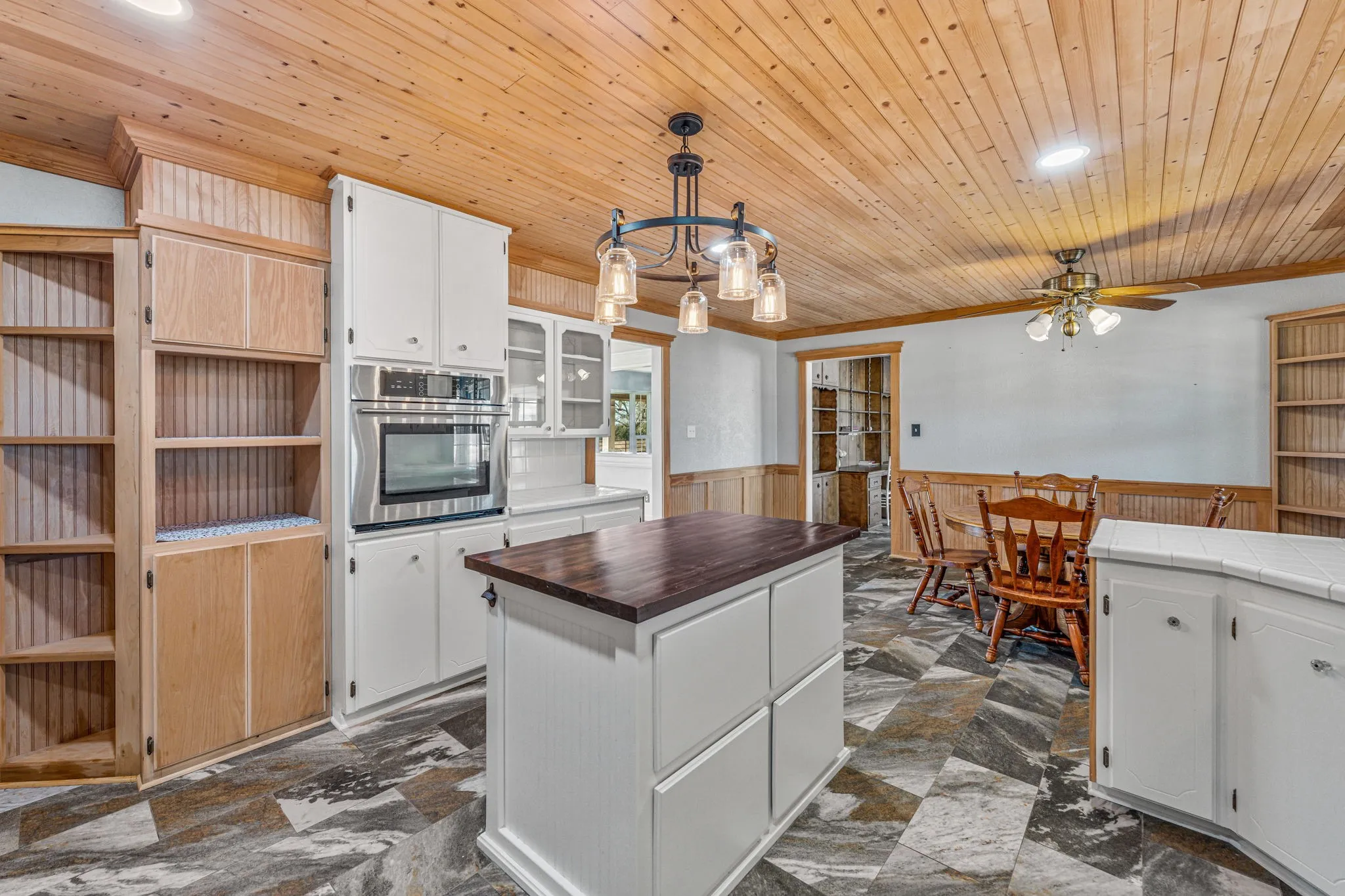Kitchen featuring a central island with a wood-finish countertop, white cabinetry with silver-tone hardware, and an integrated stainless steel oven